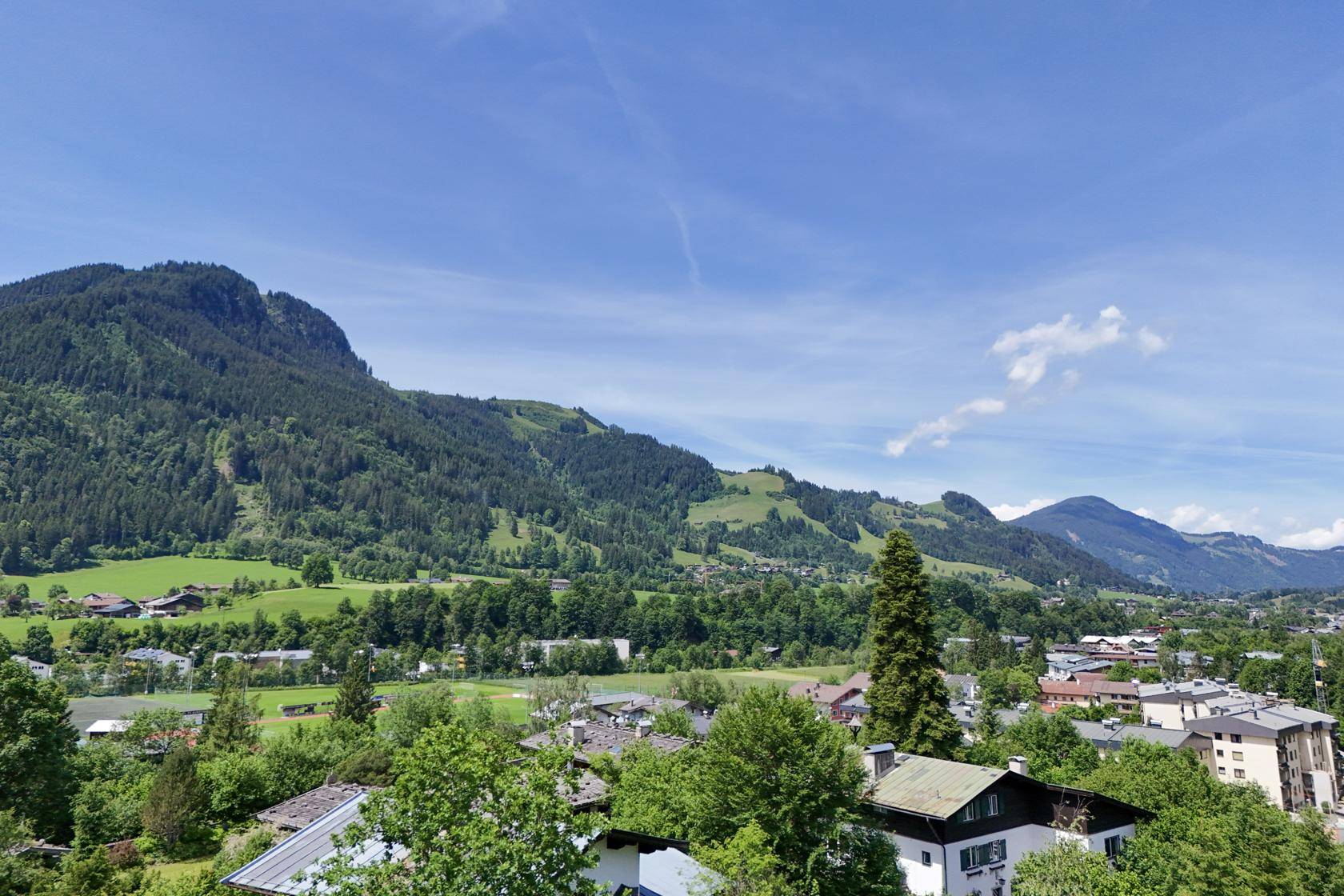 Weitläufiger Ausblick auf die grüne Berglandschaft und die Dächer der umliegenden Stadt.