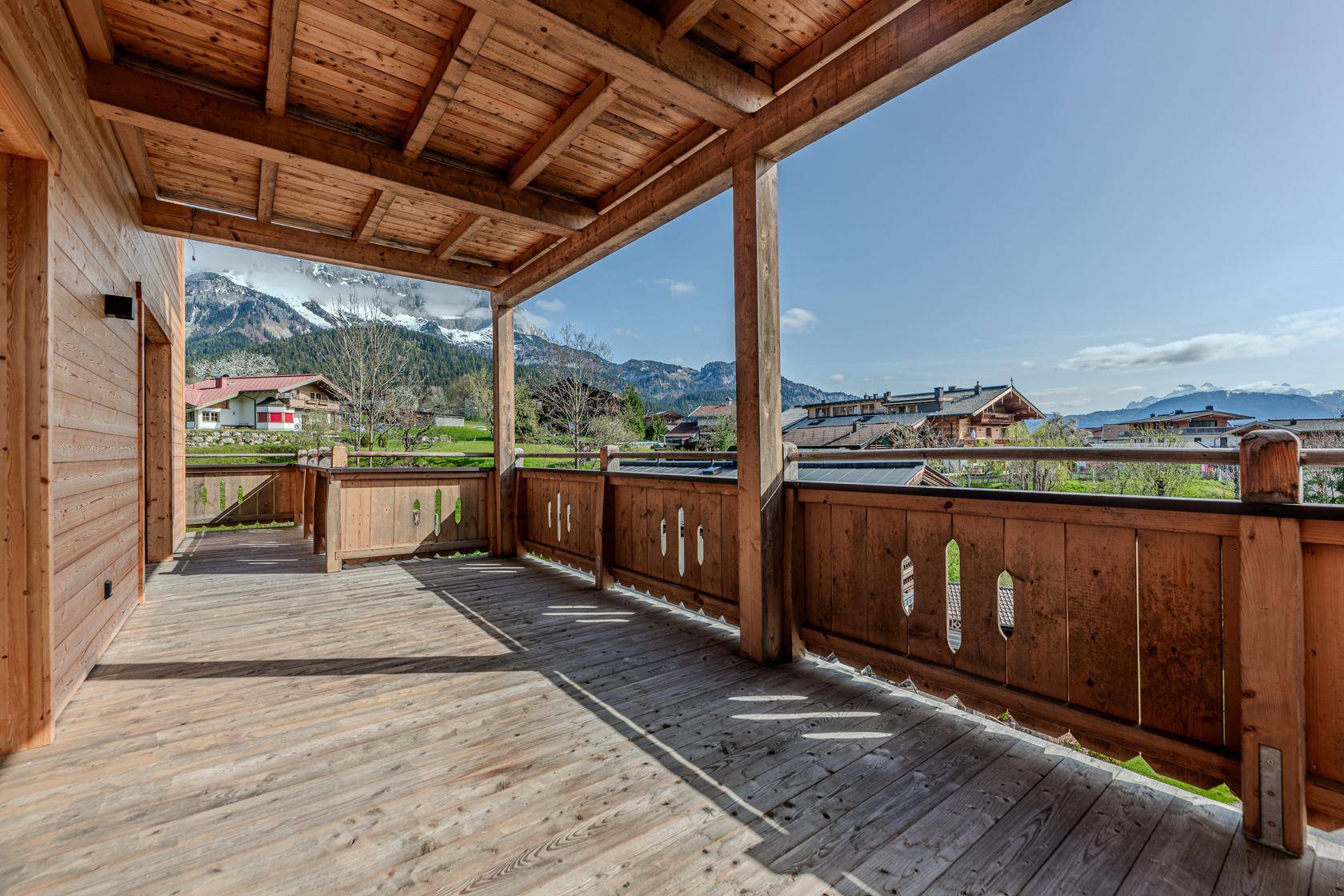 Geräumiger Holzbalkon mit traditionellem Geländer und weitem Blick auf die umliegende Berglandschaft.