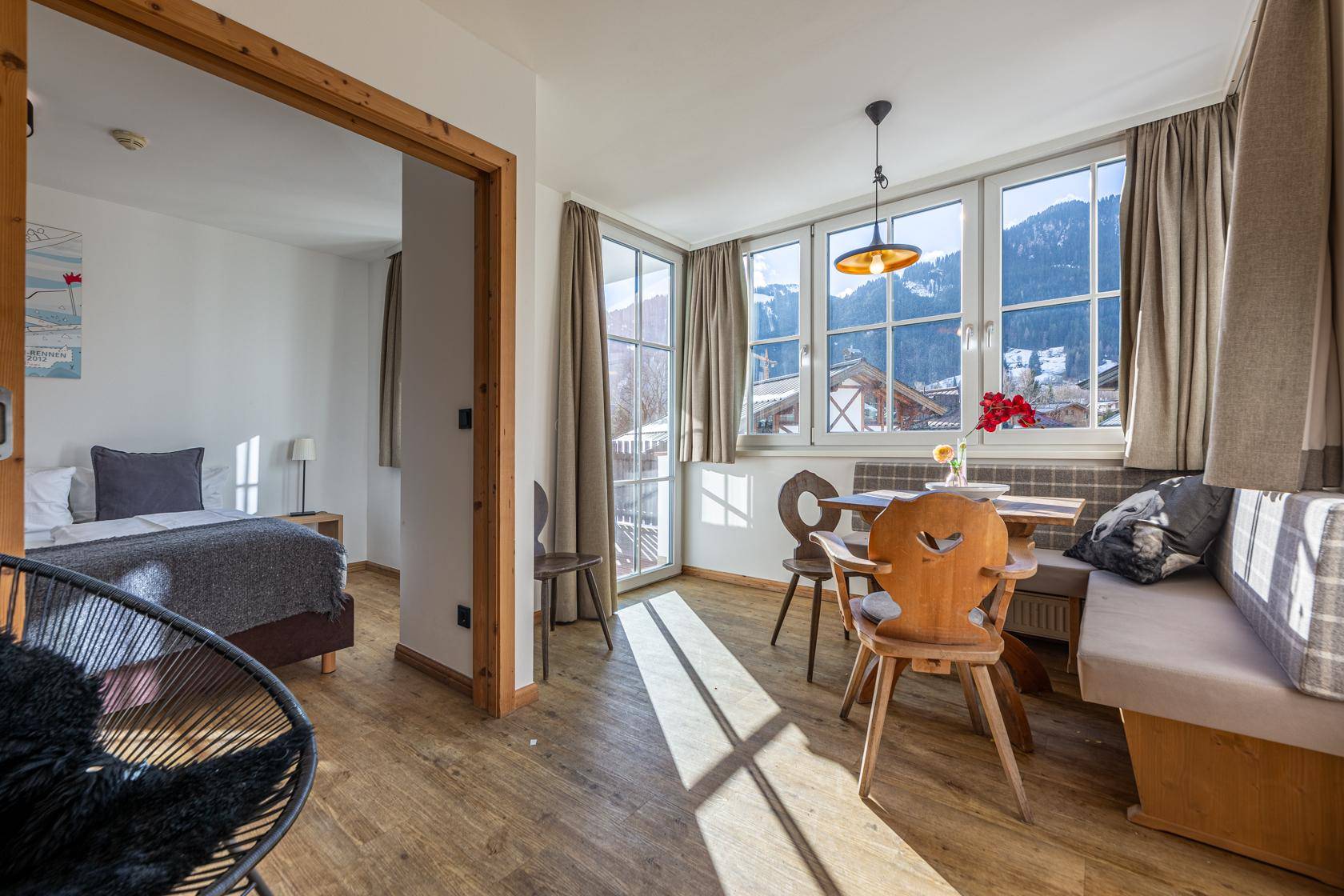 Gemütlicher Essbereich mit Holztisch und Bank, großen Fenstern und herrlichem Bergblick.