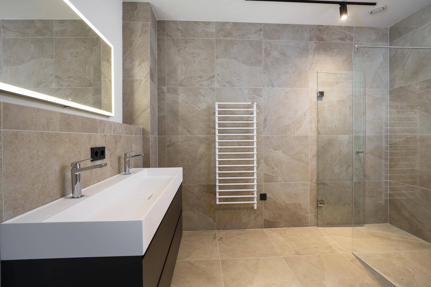 Geräumiges, modernes Badezimmer mit Doppelwaschbecken, großer begehbarer Dusche und Handtuchheizkörper.