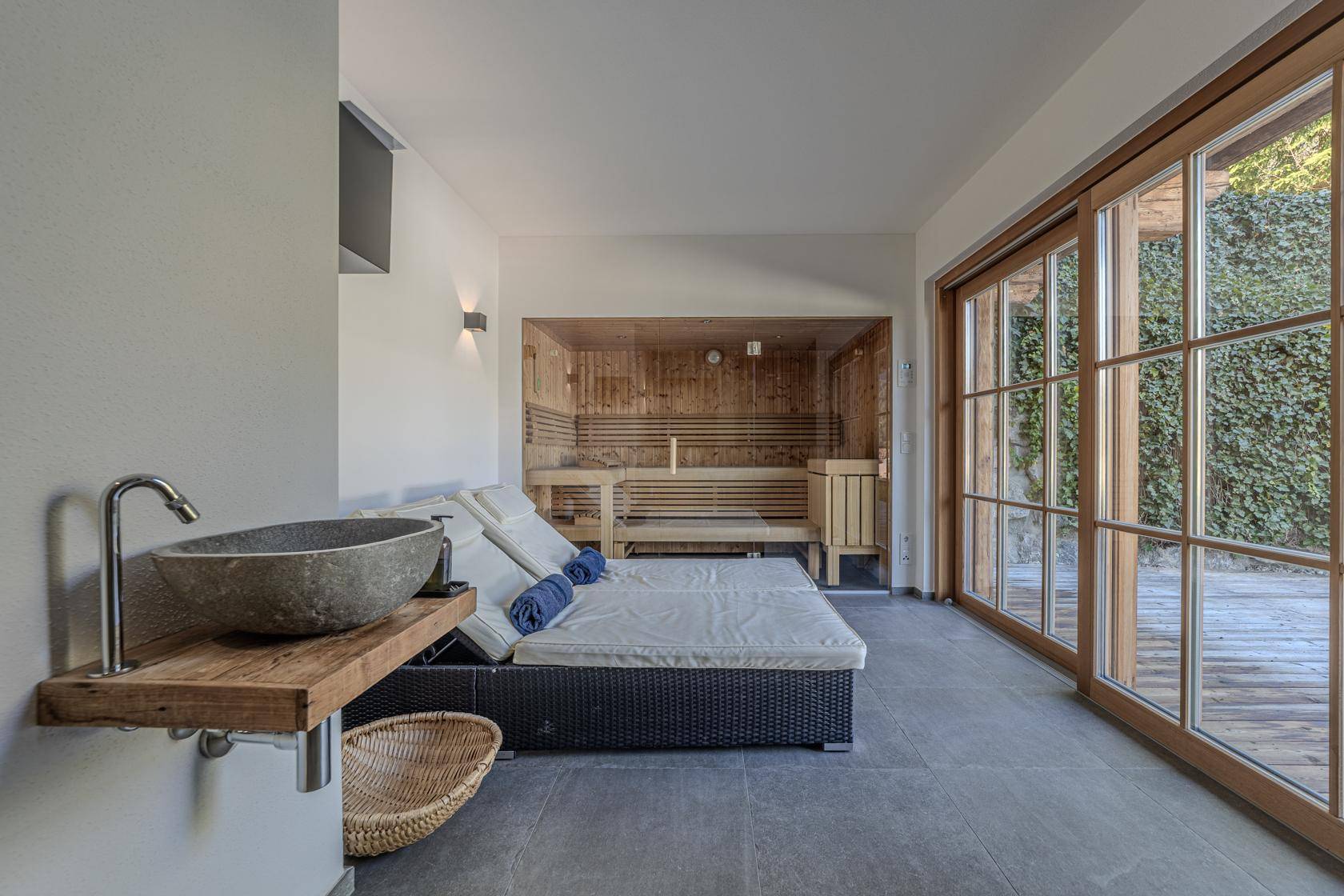 Entspannender Wellnessbereich mit Sauna, Liegen und Zugang zur Außenterrasse.