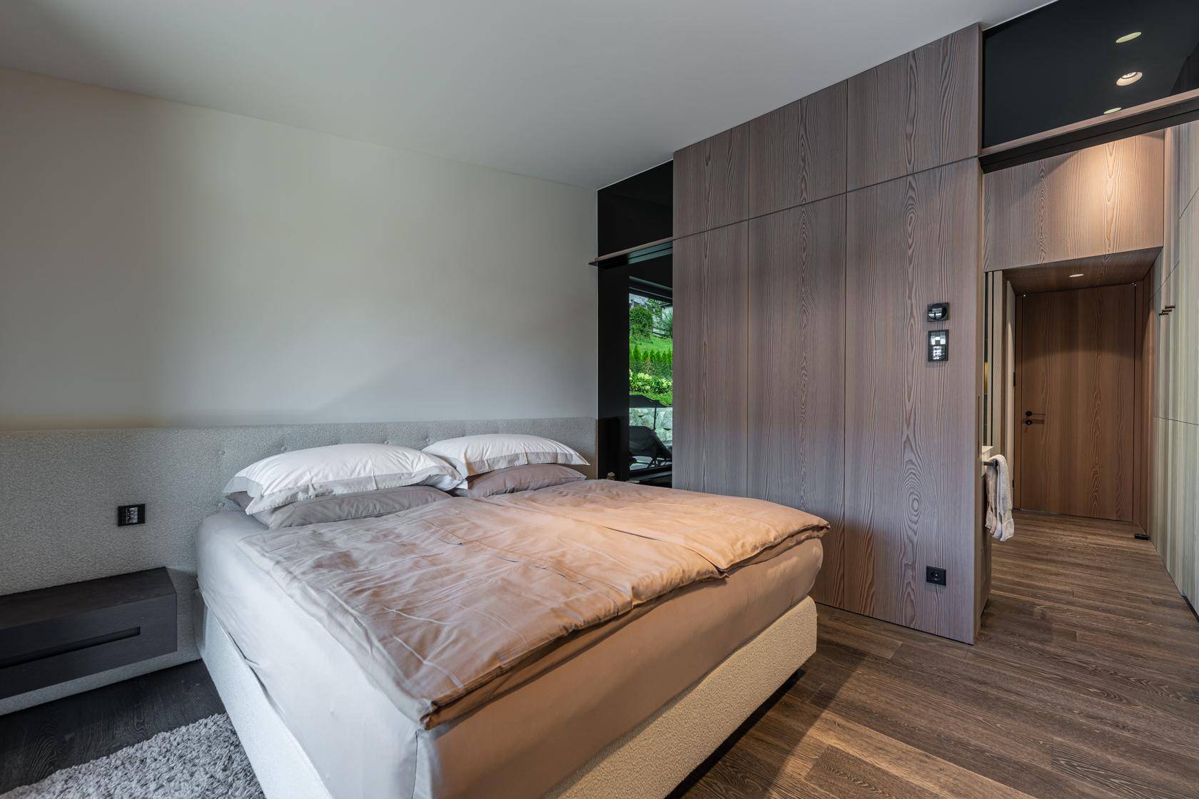 Schlafzimmer mit komfortablem Bett, integrierten Holzschränken und modernem Design.