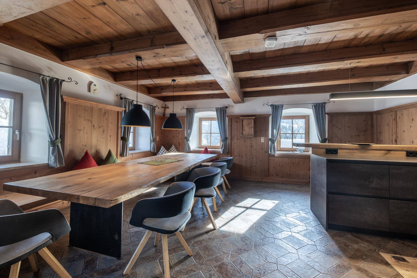 Rustikaler Essbereich mit langem Holztisch, Holzbalkendecke und Fliesenboden in traditionellem Stil.
