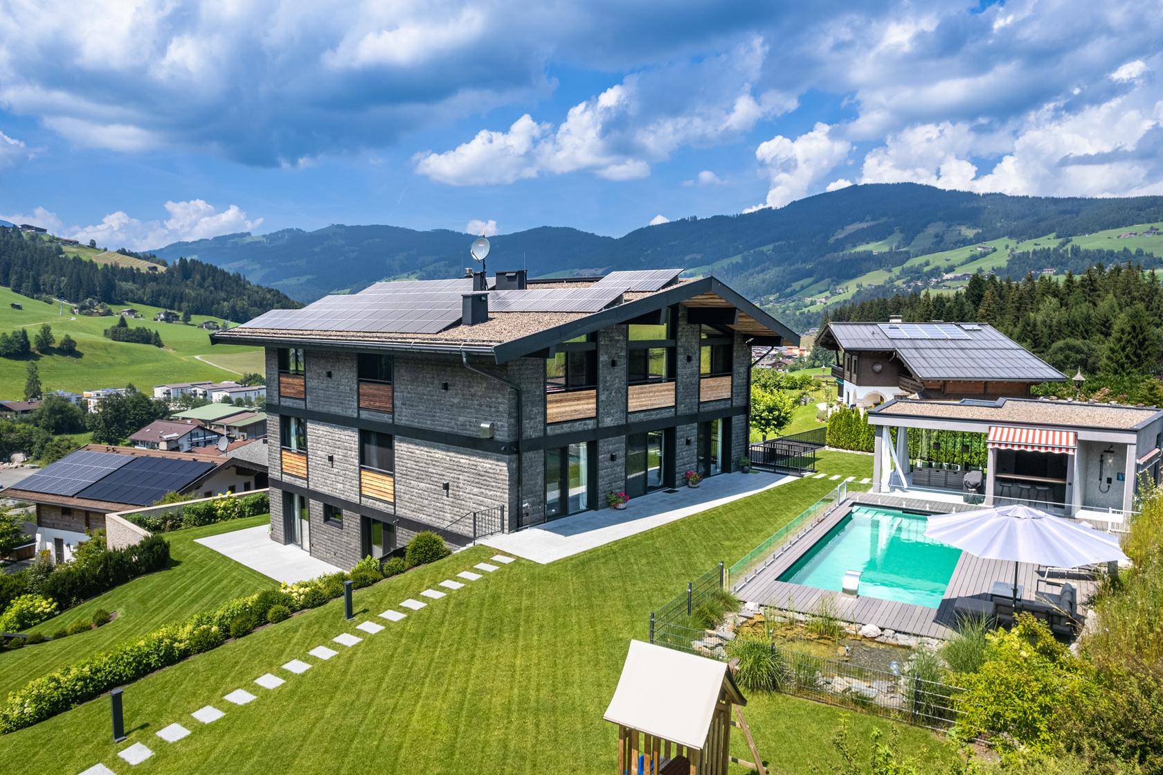 Modernes Anwesen mit Photovoltaikanlage, Pool, Garten und beeindruckendem Bergblick.