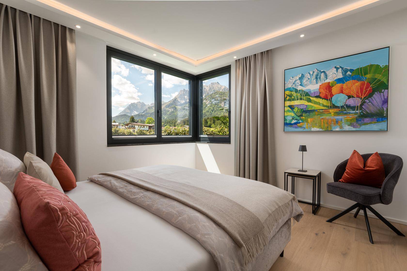 Schlafzimmer mit Doppelbett, Holzboden und Panoramafenstern mit Bergblick.