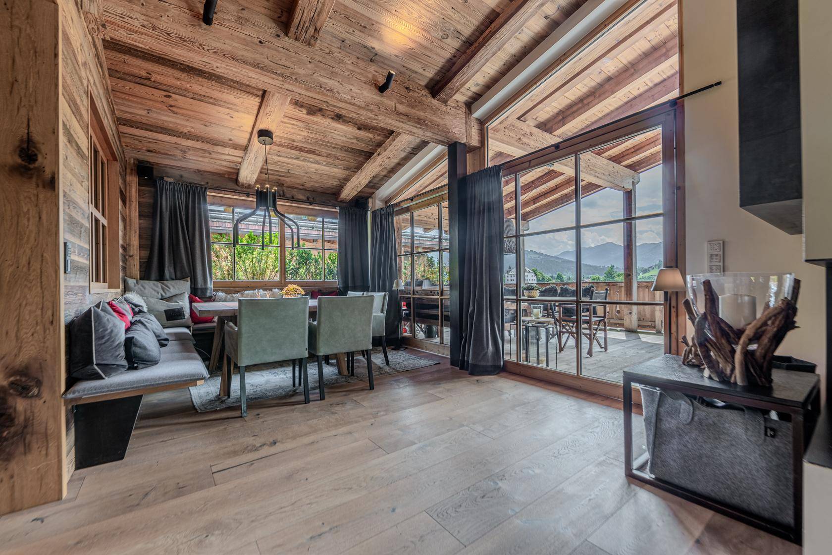 Heller Essbereich mit Holztisch, Sitzbank und direktem Zugang zur Terrasse mit Bergblick.