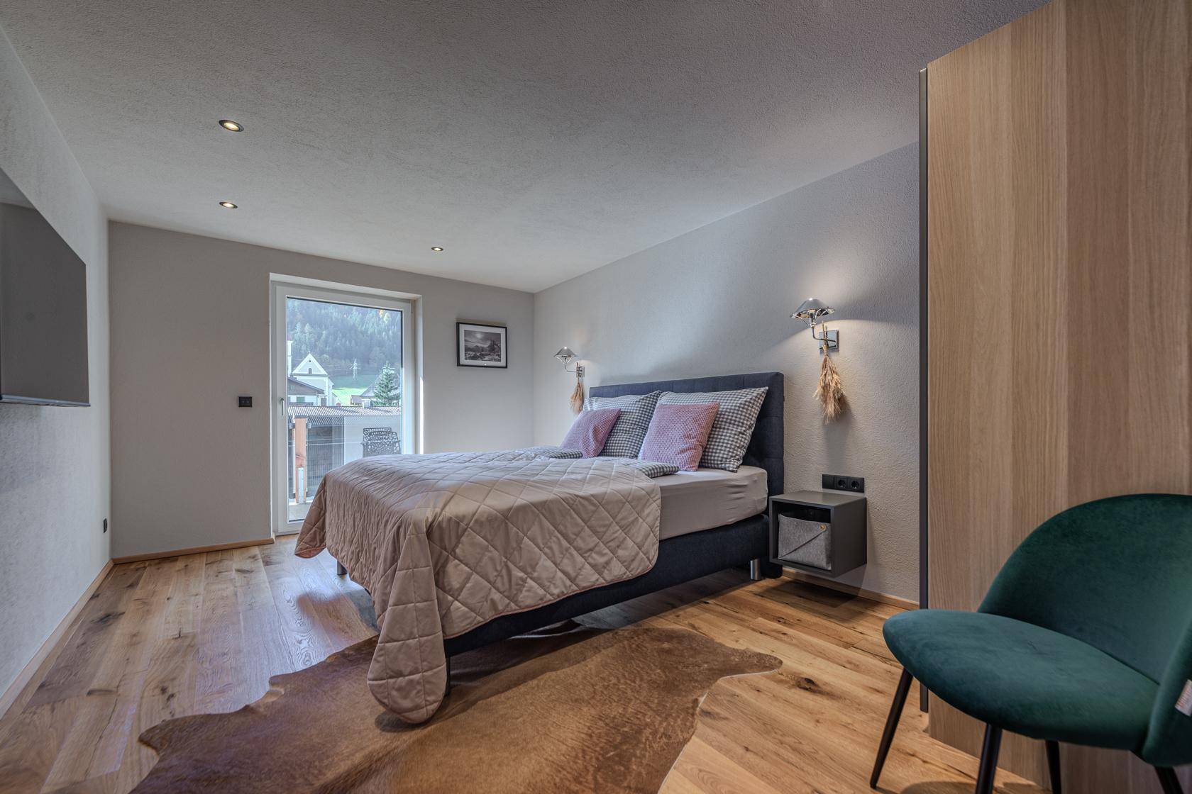 Komfortables Schlafzimmer mit Holzboden, Balkonzugang und moderner Einrichtung.