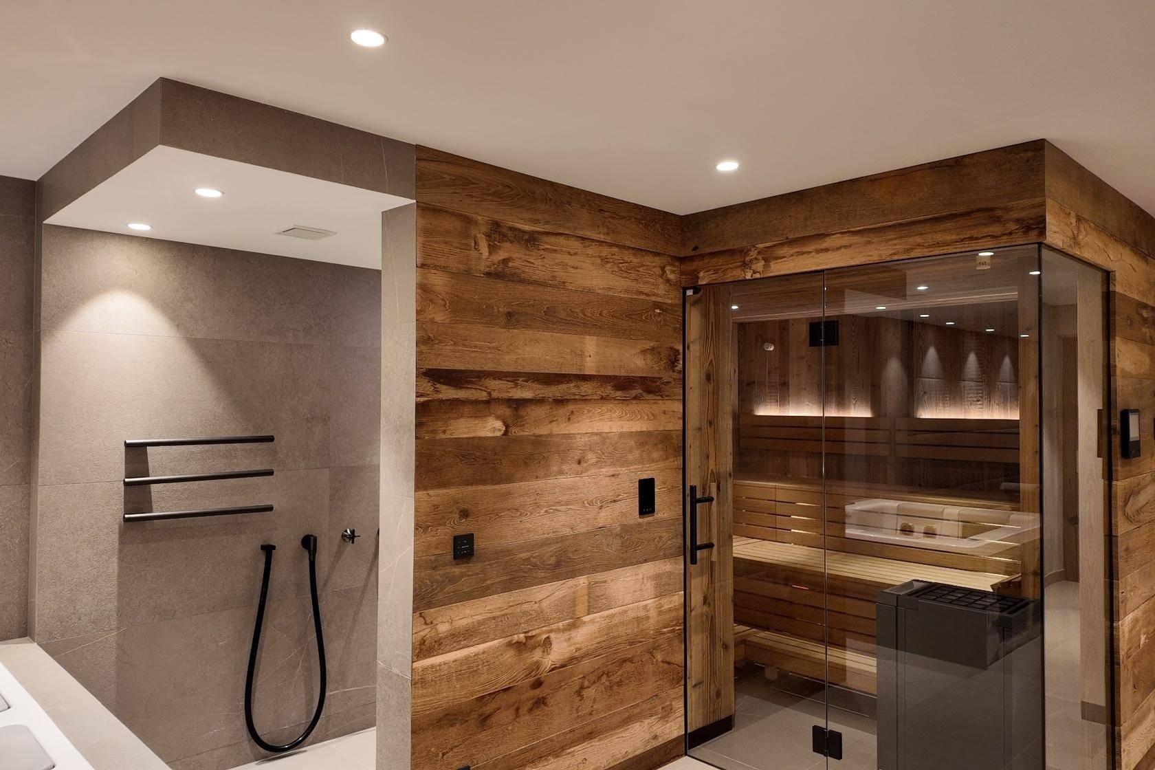 Moderner Wellnessbereich mit Holzsauna, Regendusche und beheiztem Handtuchhalter.