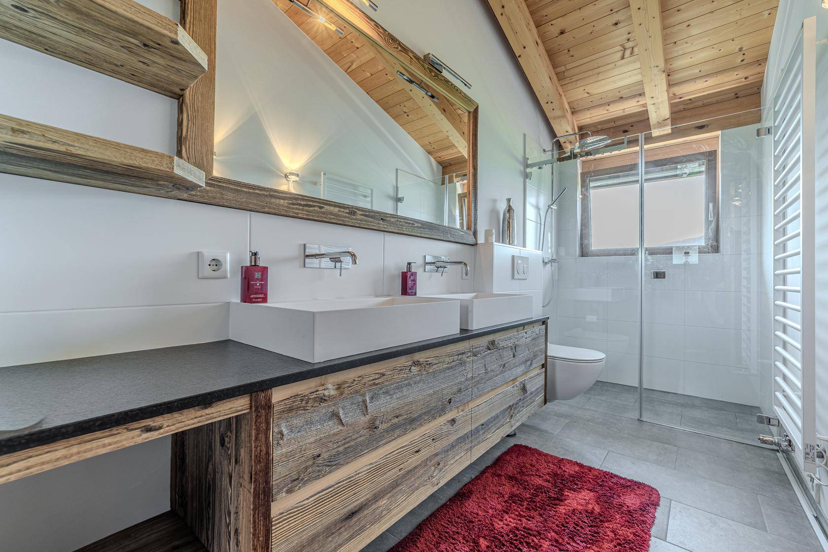 Geräumiges Badezimmer mit Doppelwaschbecken, großer Dusche und beheiztem Handtuchhalter.