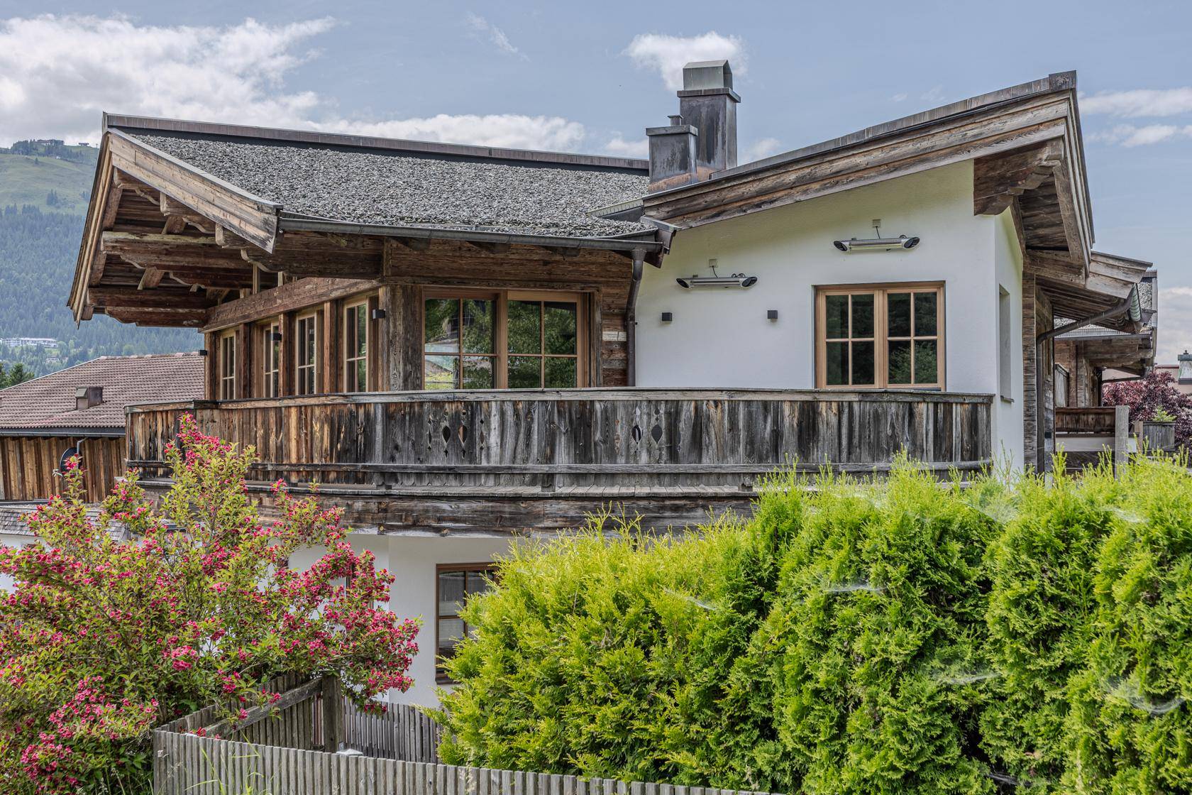Alpines Holzhaus mit traditioneller Architektur, Balkonen und grüner Umgebung.