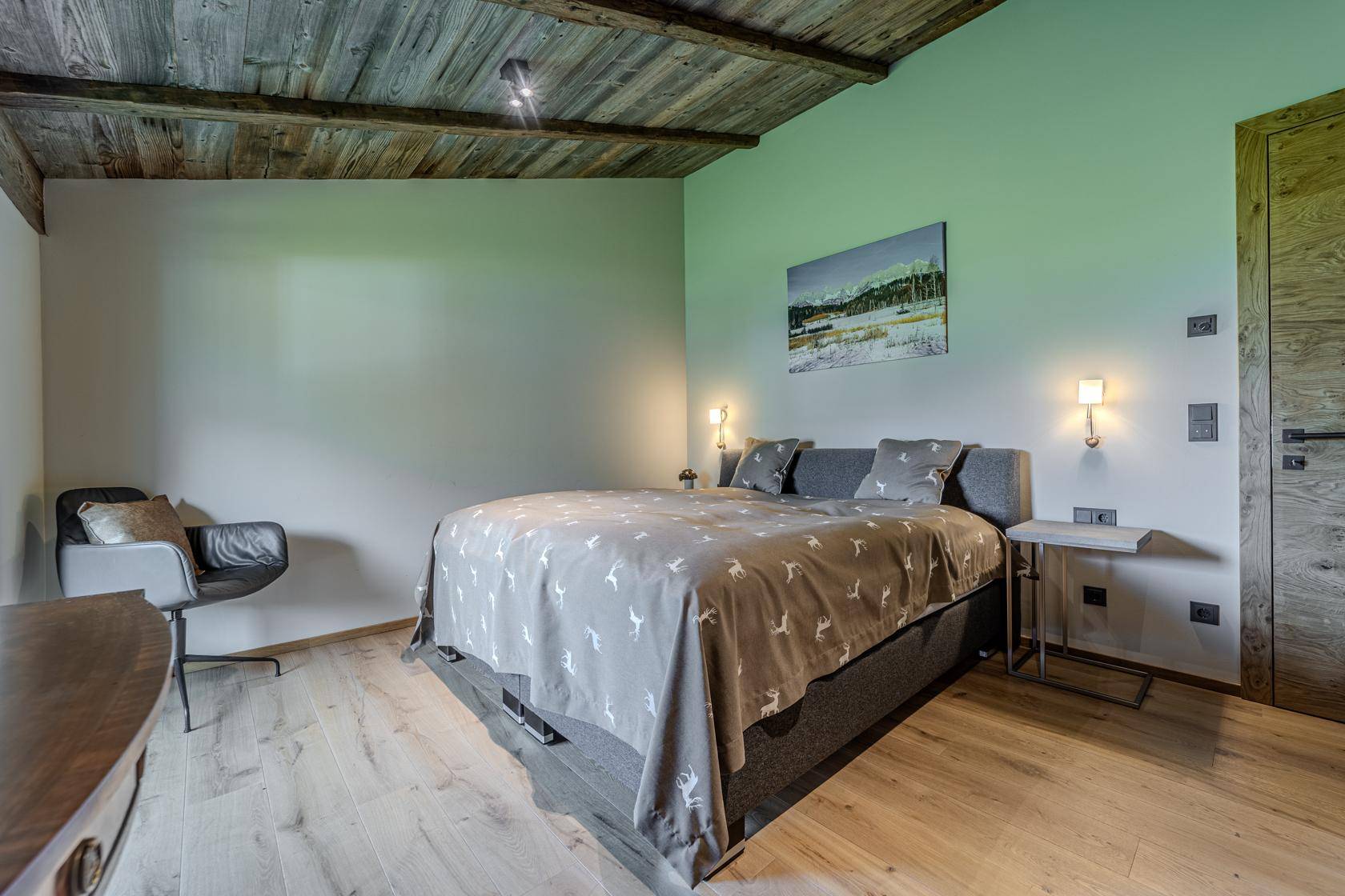 Gemütliches Schlafzimmer mit Holzboden, modernem Bett und Fenster mit Blick ins Grüne.