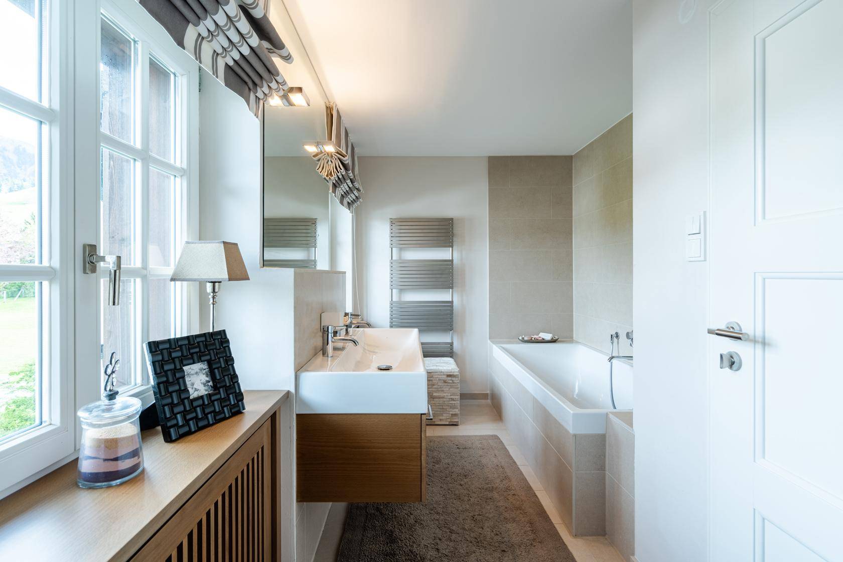 Modernes Badezimmer mit Badewanne, Einzelwaschbecken und beheiztem Handtuchhalter.