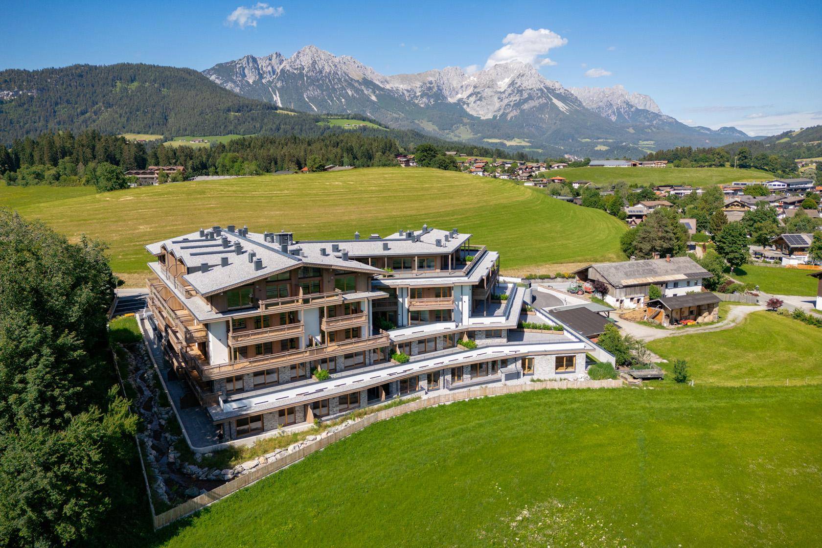 Exklusives Wohngebäude in idyllischer Lage mit Panoramablick auf die Alpen und grüne Hügel.