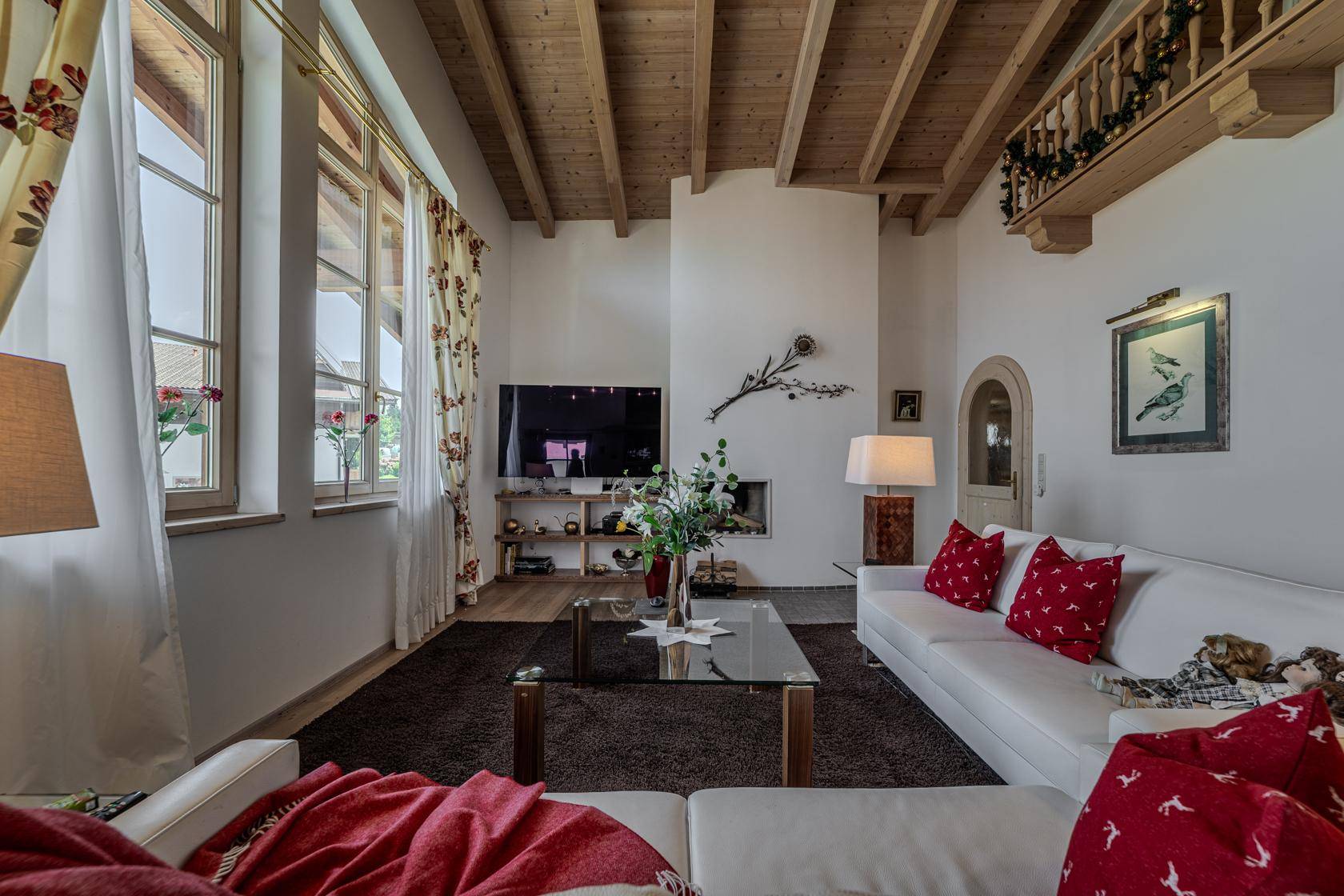 Helles Wohnzimmer mit hohen Holzdecken, großen Fenstern und einem modernen Kaminbereich.