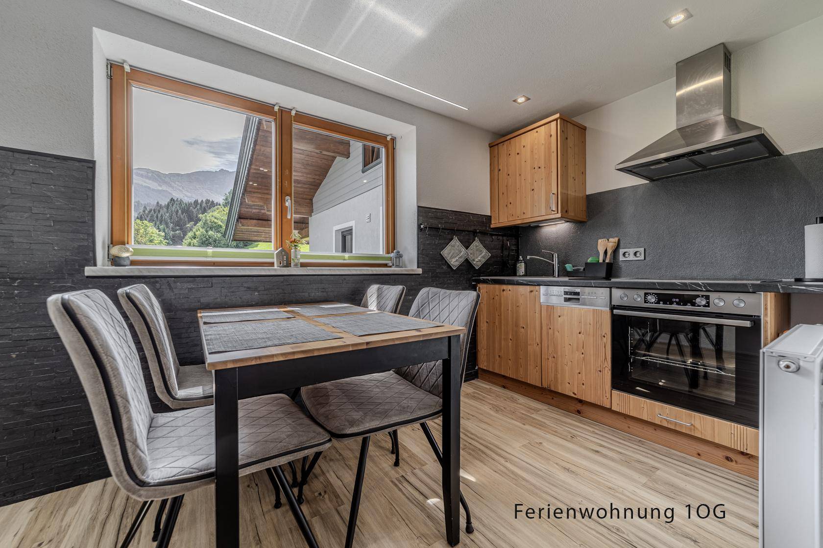 Küche mit Holzeinbauschränken, Essbereich und Fenster mit Bergblick.