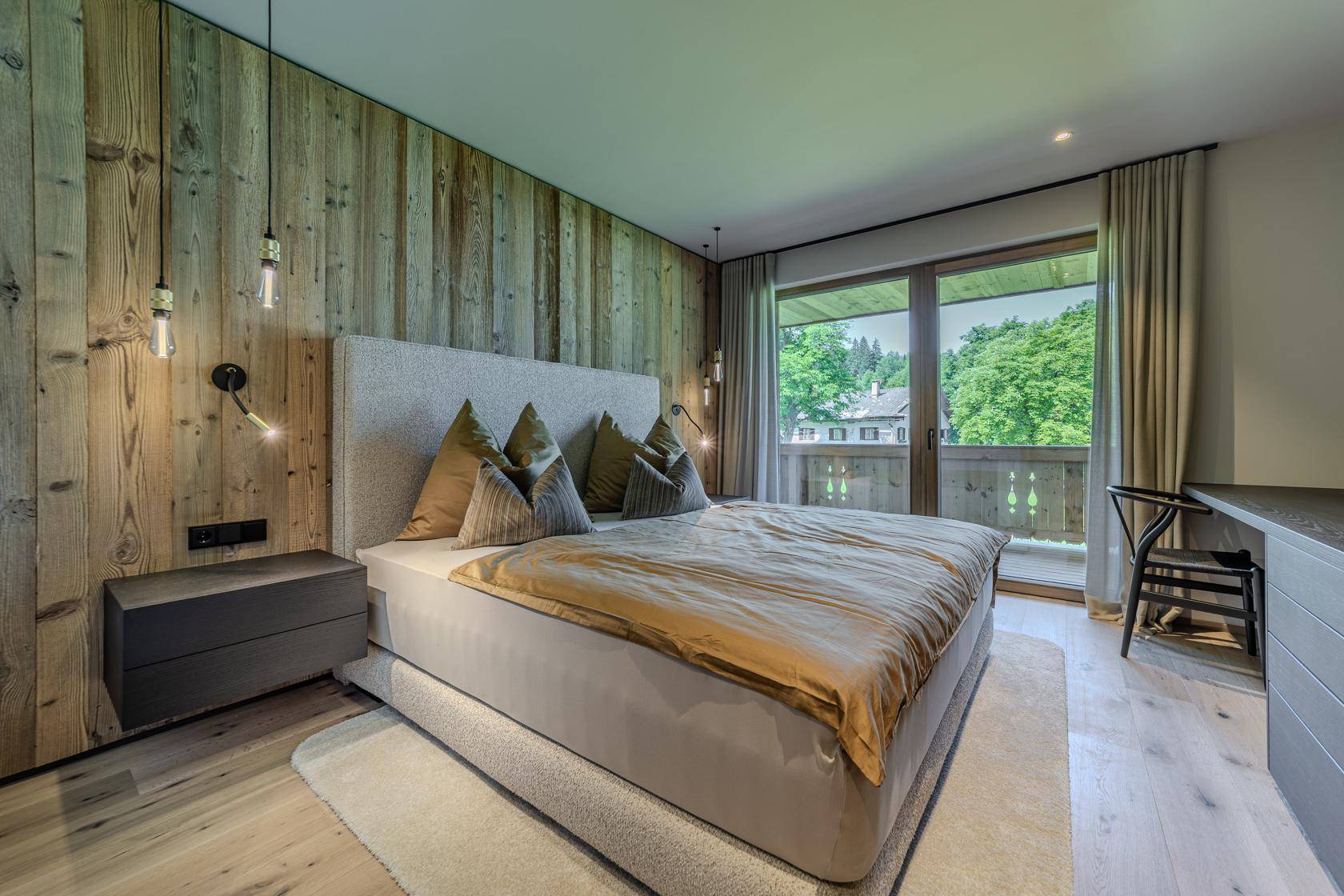 Helles Schlafzimmer mit Holzwand, großem Bett und Zugang zu einem Balkon mit Aussicht.