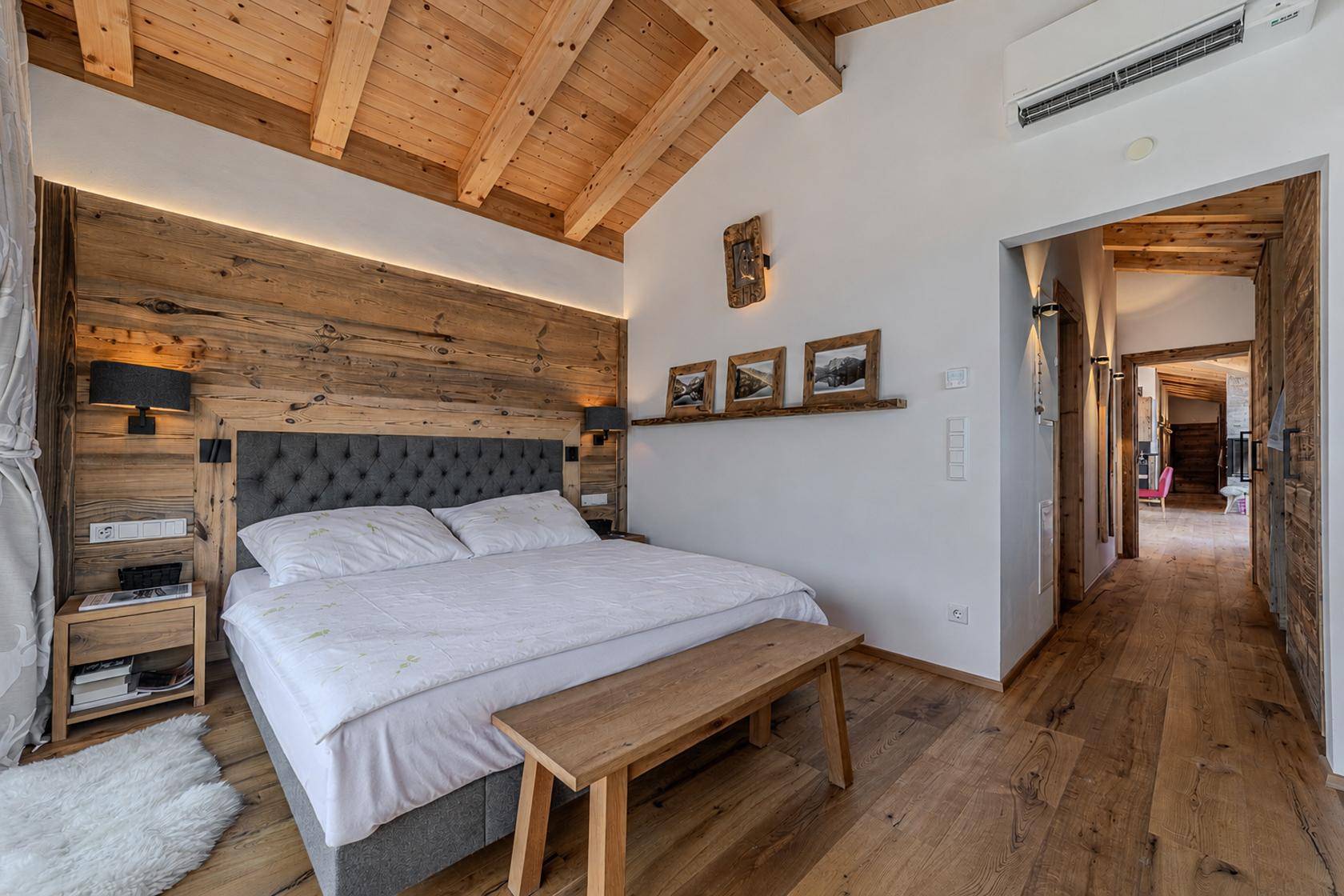 Helles Schlafzimmer mit Holzwänden, Klimaanlage und Zugang zum Flur.