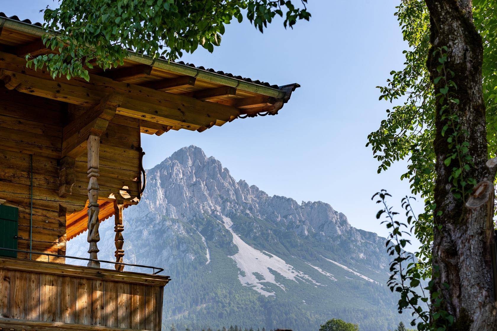Detailansicht eines Holzhauses mit Balkon und beeindruckendem Blick auf die Berge.