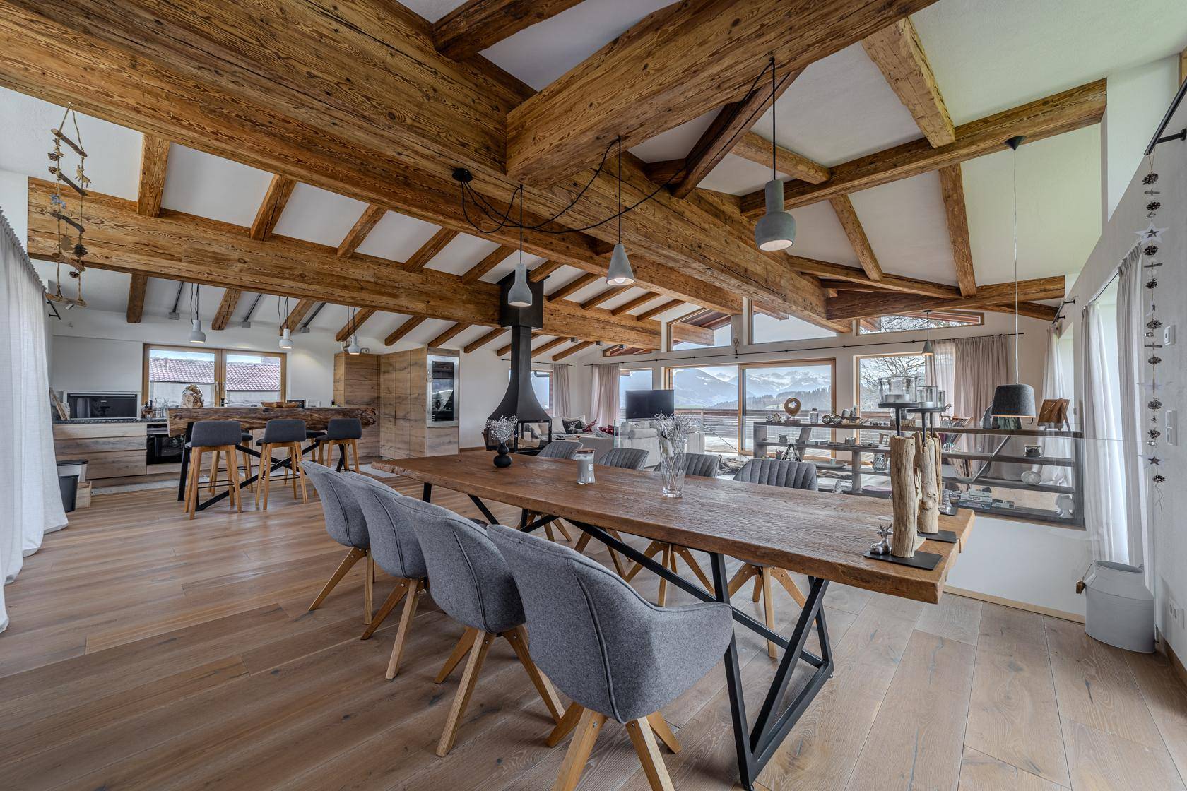 Offener Wohn- und Essbereich mit großem Holztisch, moderner Küche und Bergblick.