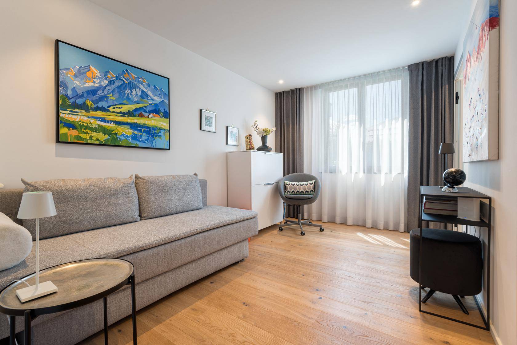 Gemütliches Wohnzimmer mit Sofa, Holzboden und Blick auf die Berge.