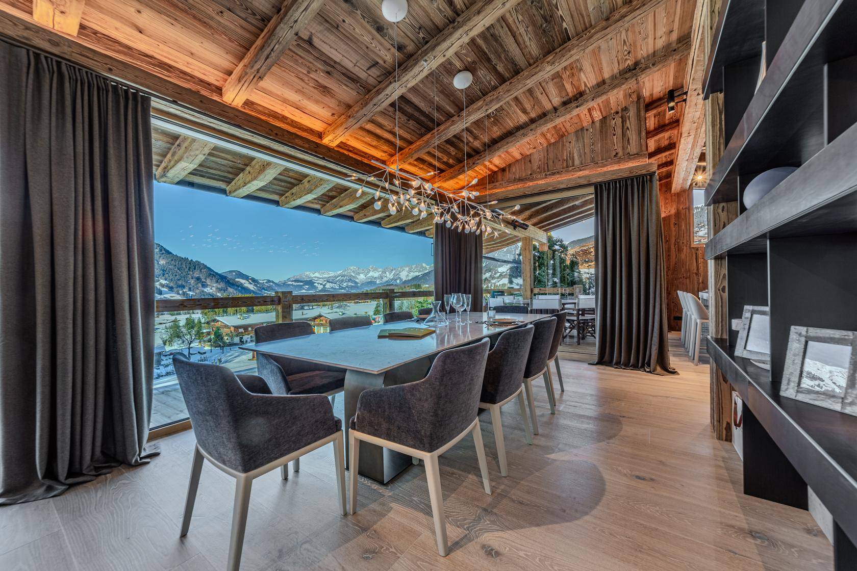 Eleganter Essbereich mit Holzbalkendecke und raumhohen Fenstern, die einen weiten Bergblick bieten.