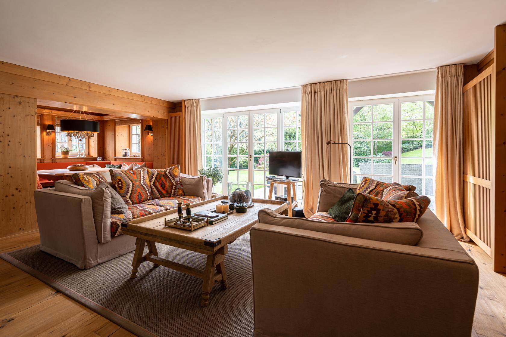 Geräumiges Wohnzimmer mit bequemen Sofas, Holzboden und Zugang zum Garten.