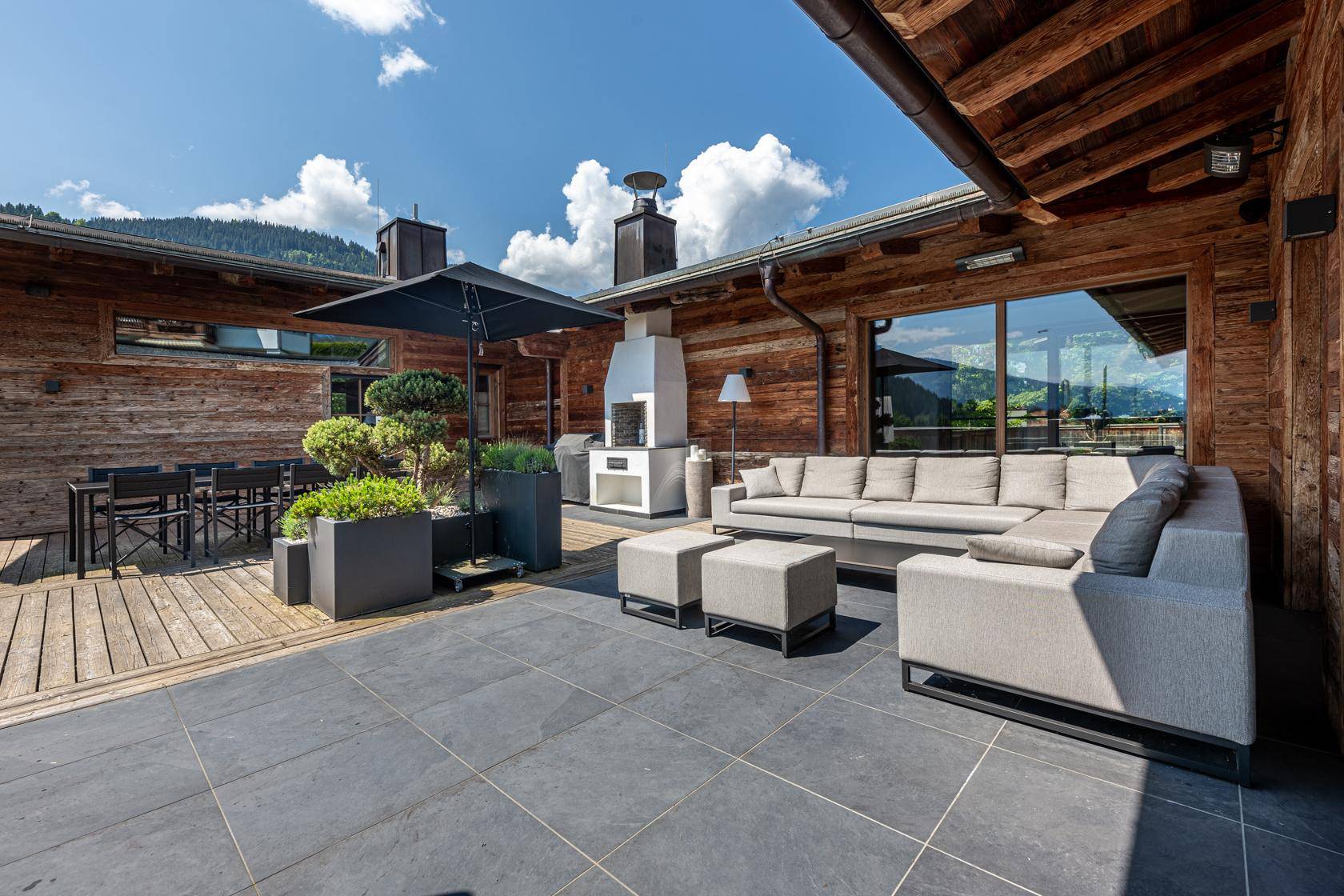 Große Terrasse mit Lounge-Bereich, Grillkamin und Blick auf die umliegende Berglandschaft.