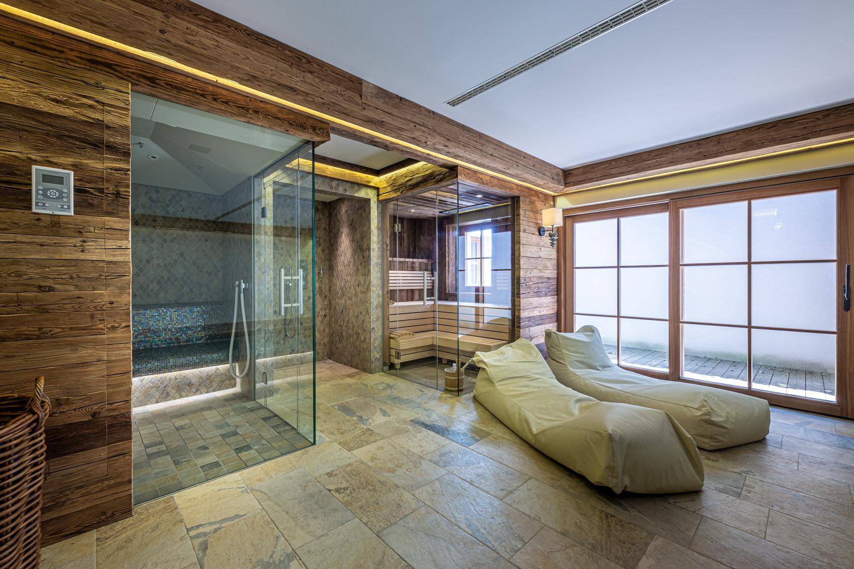 Moderner Wellnessbereich mit Sauna, Dampfbad und Liegeflächen, umgeben von Holz und Stein.