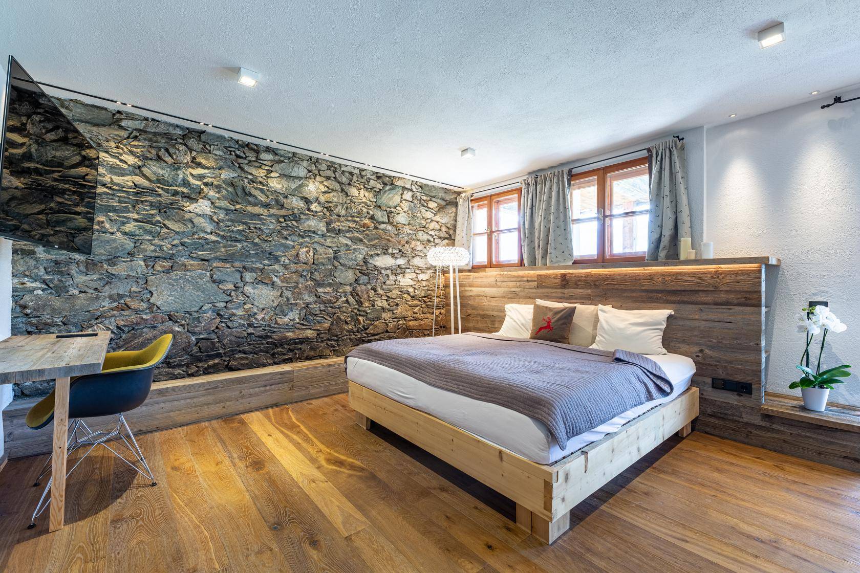 Helles Schlafzimmer mit Holzboden, Steinwand und moderner Einrichtung.