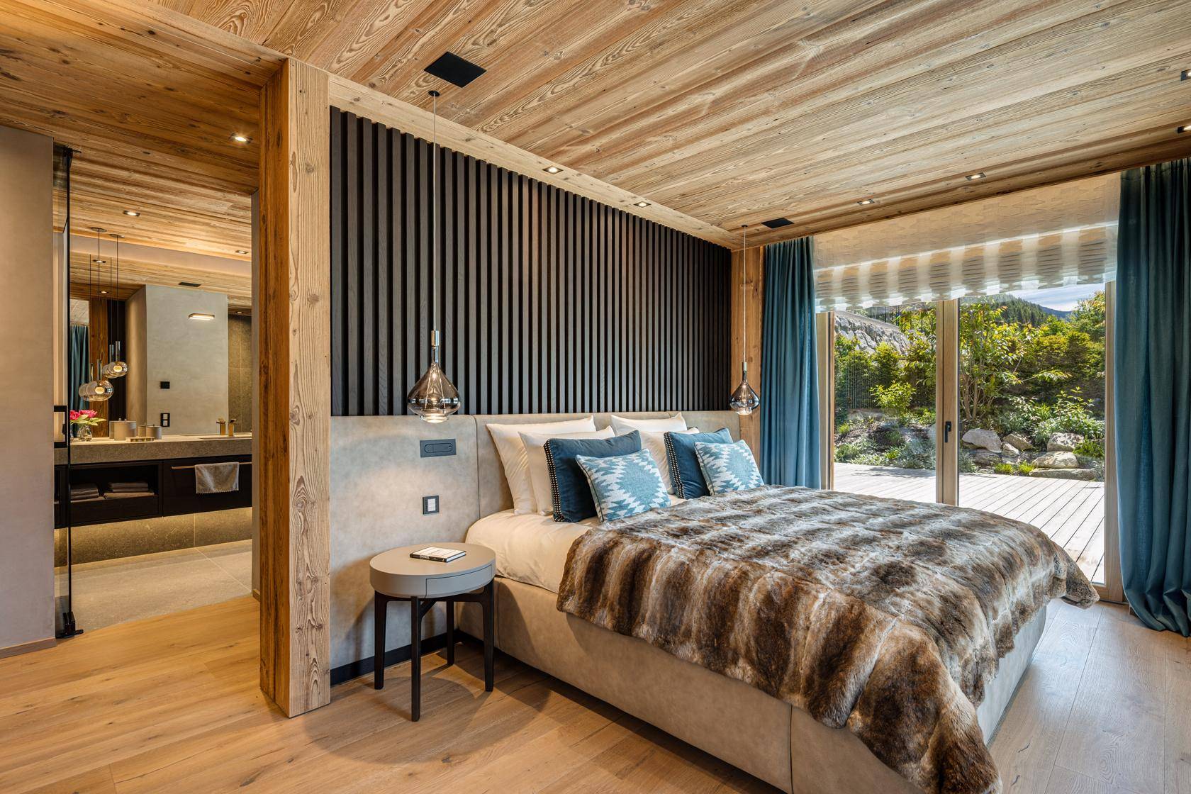Gemütliches Schlafzimmer mit Holzwänden, Zugang zur Terrasse und offenem Badezimmerbereich.