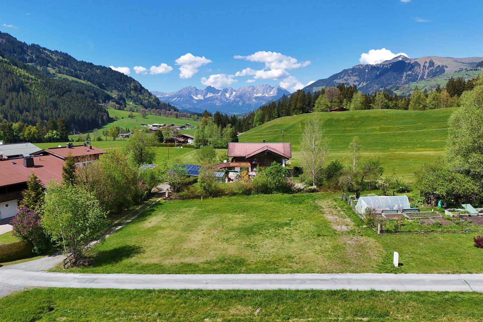 Panoramablick auf ein idyllisches Anwesen mit weiten Grünflächen und majestätischem Alpenpanorama.