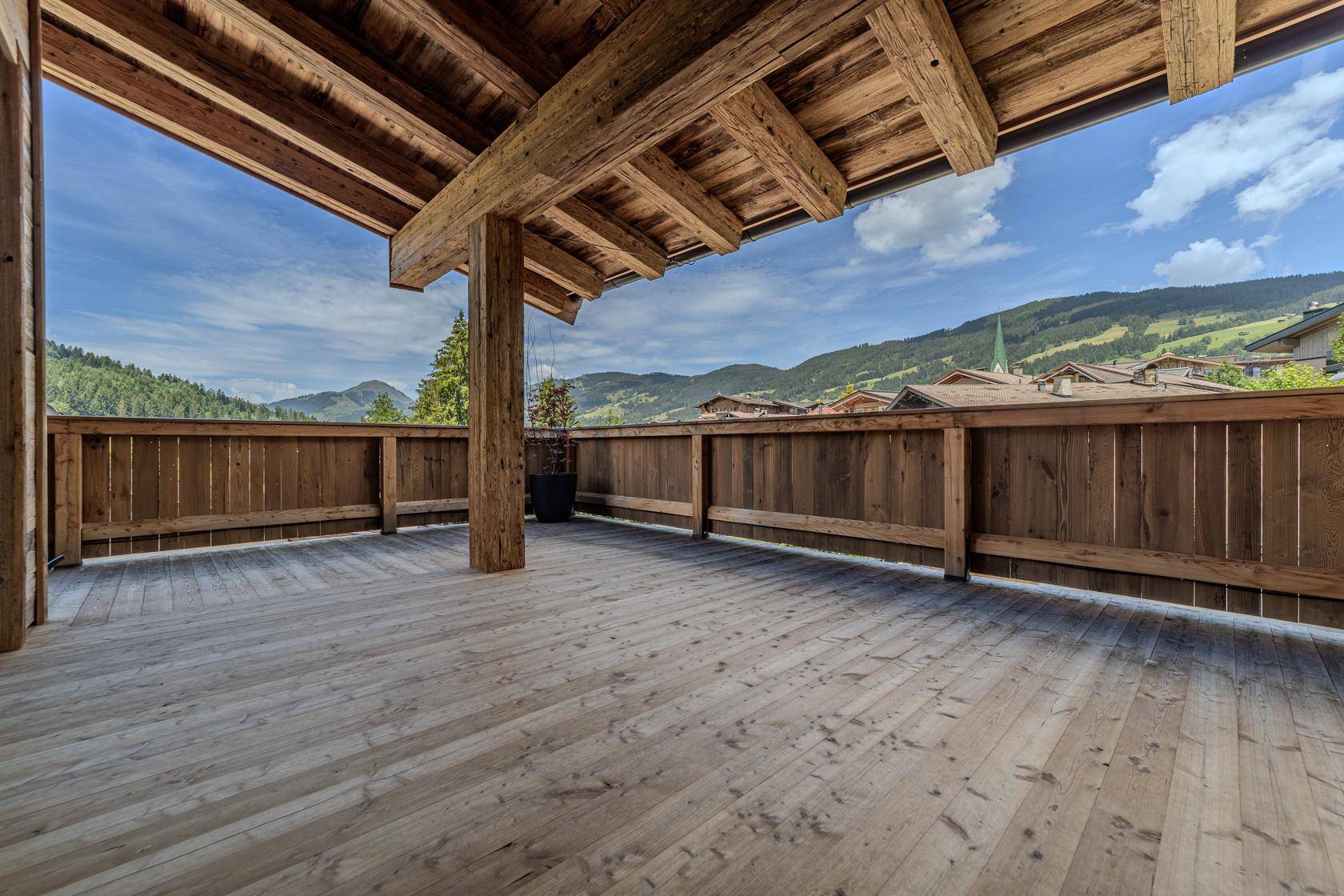 Große Holzterrasse mit Bergblick und Holzbalken, ideal für Entspannung im Freien.