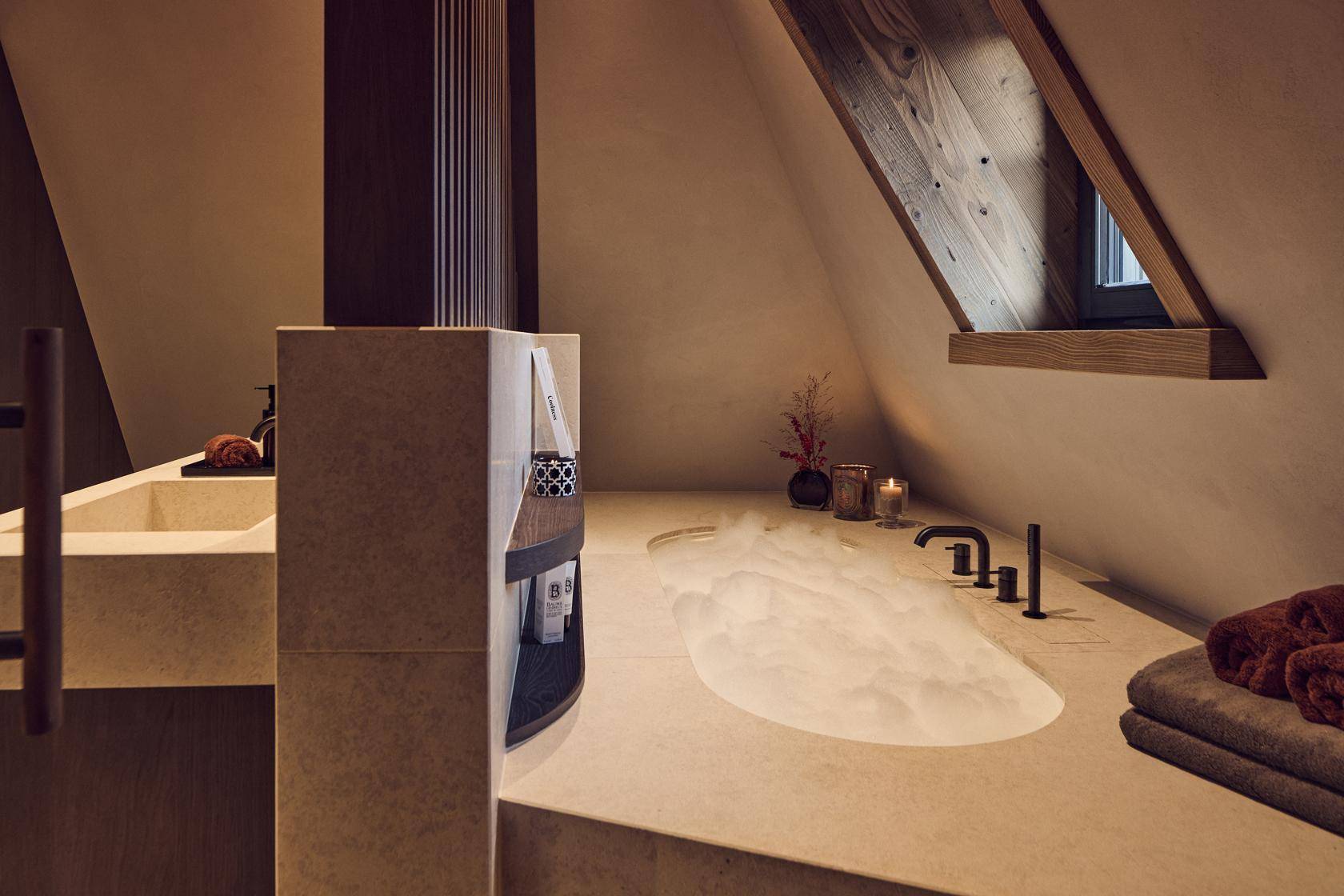 Luxuriöses Badezimmer mit eingelassener Badewanne, Dachschräge und hochwertigen Armaturen.