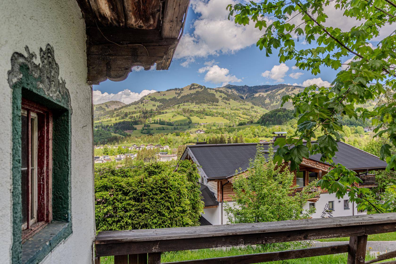 Blick vom Balkon auf die grüne Hügellandschaft und ein charmantes Dorf in der Ferne.
