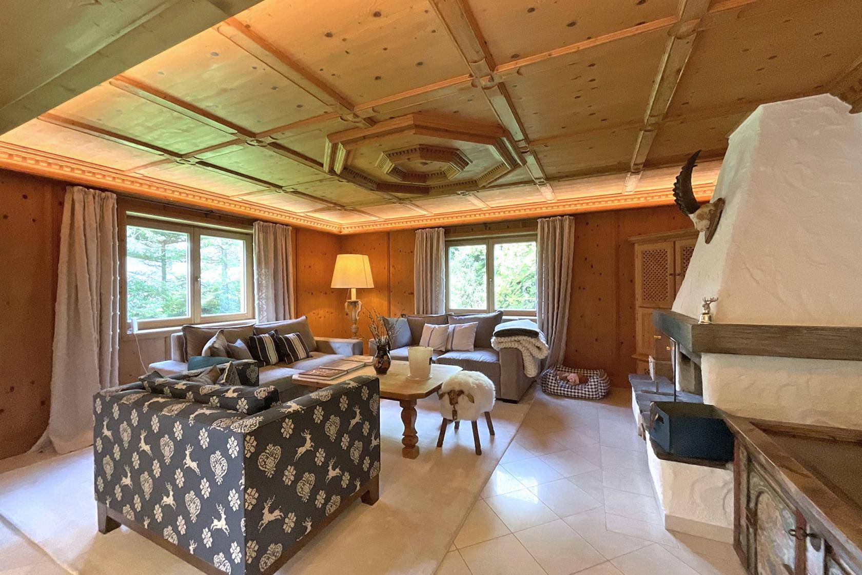Geräumiges Wohnzimmer mit traditioneller Holzausstattung, Kamin und Blick ins Grüne.