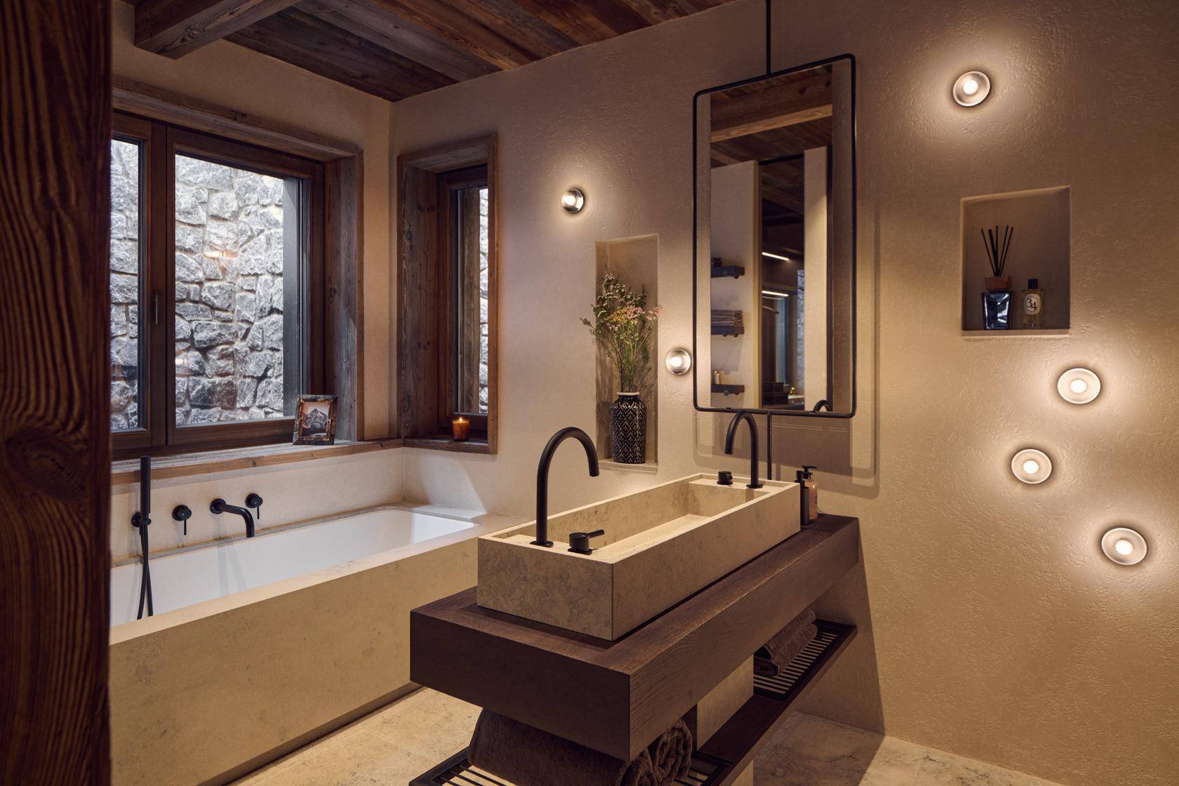 Modernes Badezimmer mit Doppelwaschbecken, Badewanne und Fenster mit Steinwandblick.