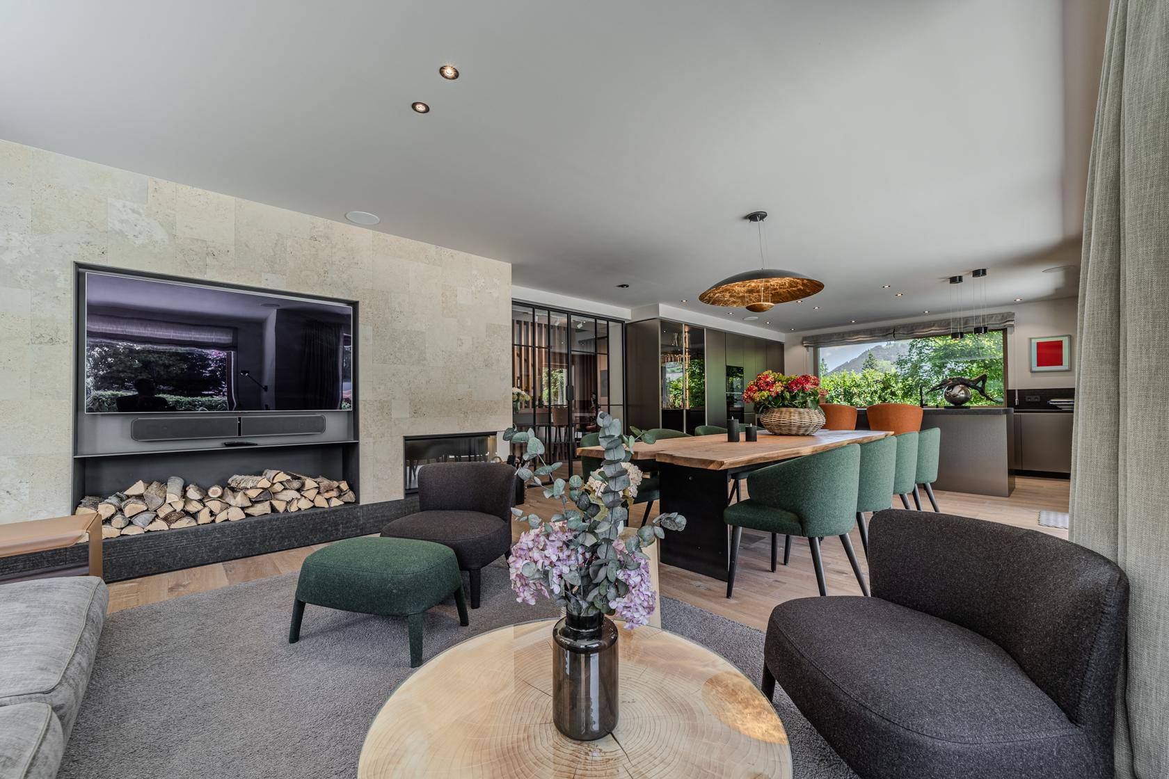 Gemütlicher Wohnbereich mit Kamin, großem Sofa und Blick auf den Essbereich und die moderne Küche.