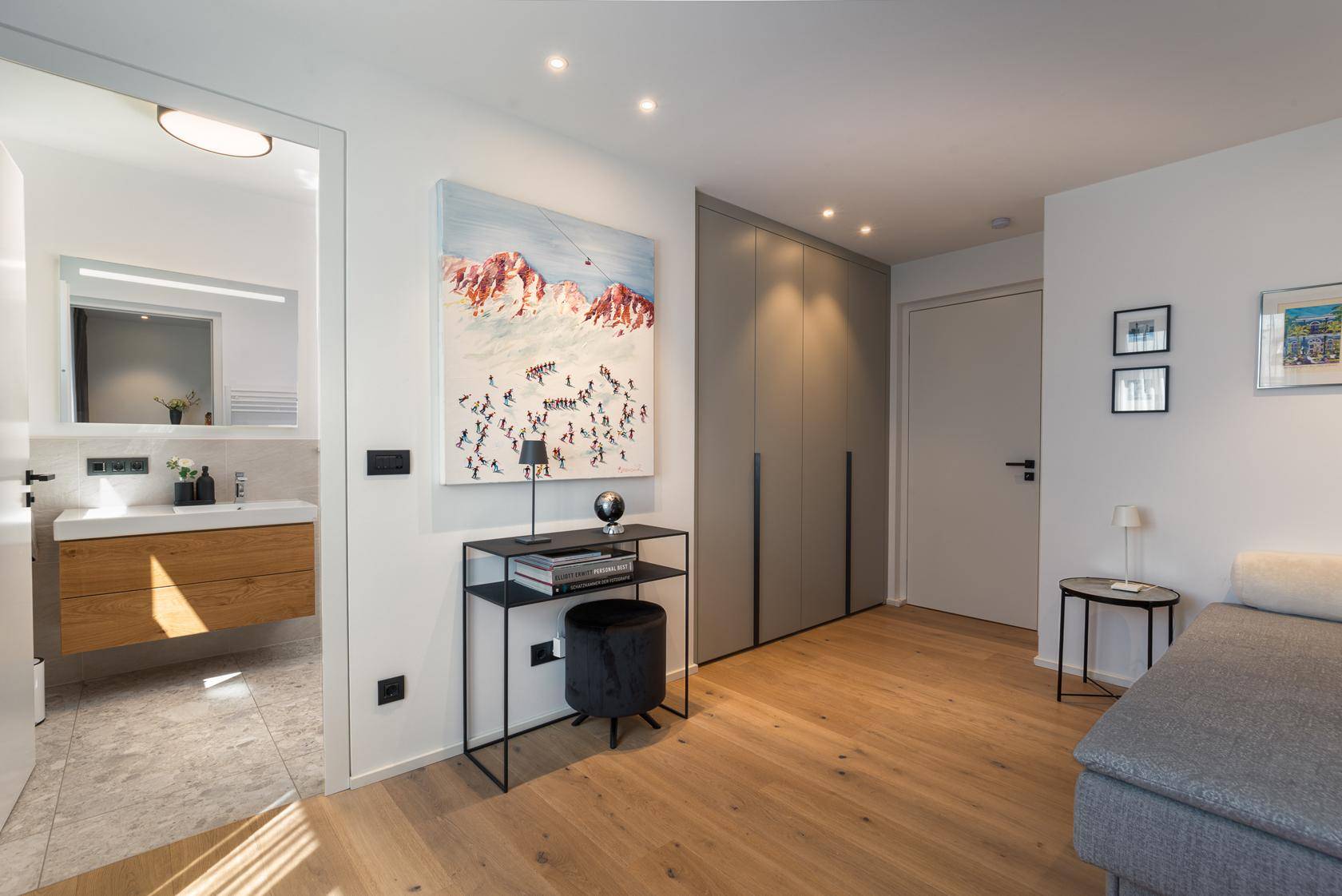 Schlafzimmer mit Einbauschränken, Holzboden und direktem Zugang zum Badezimmer.