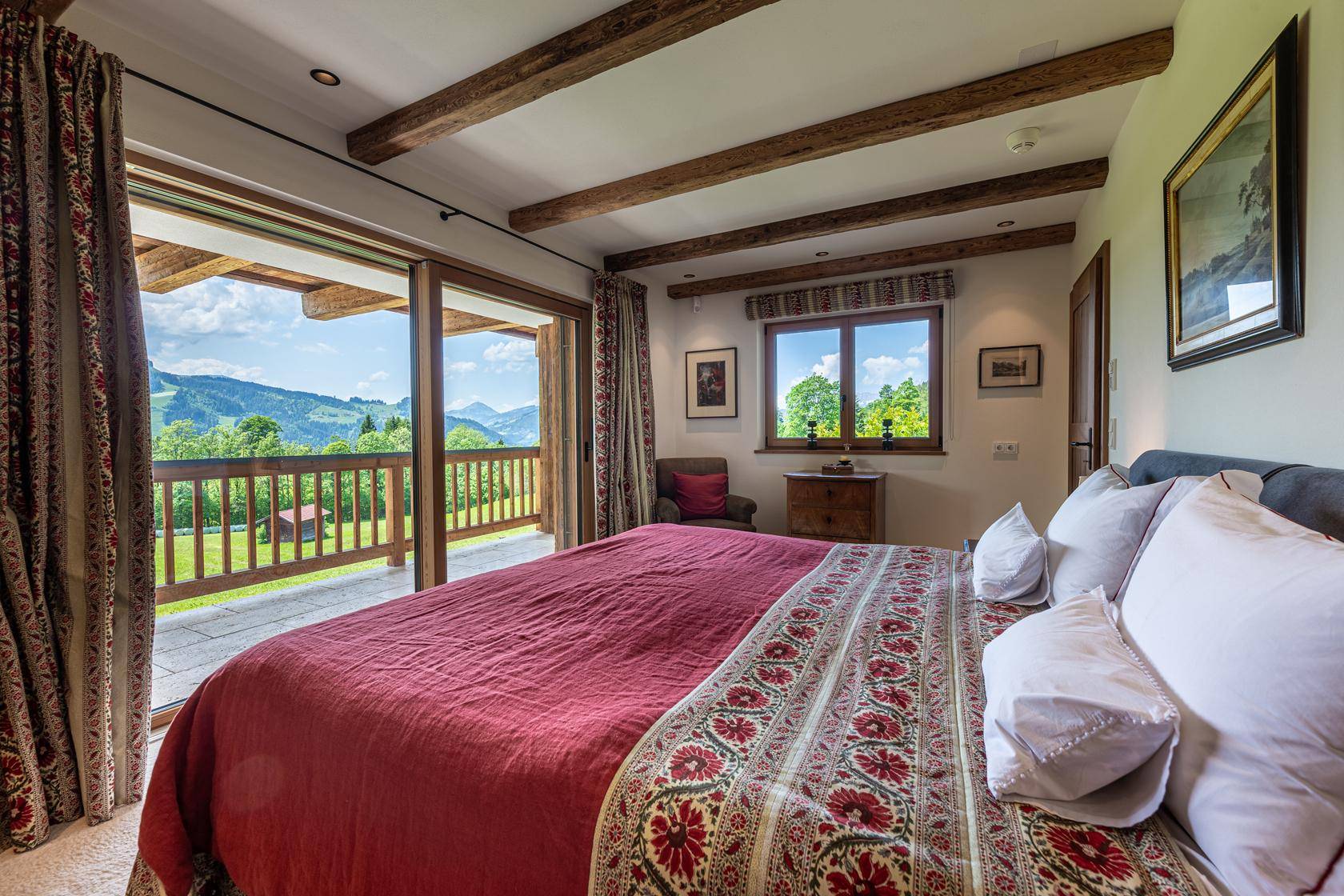 Gemütliches Schlafzimmer mit Holzbalken, Balkonzugang und herrlichem Bergblick.
