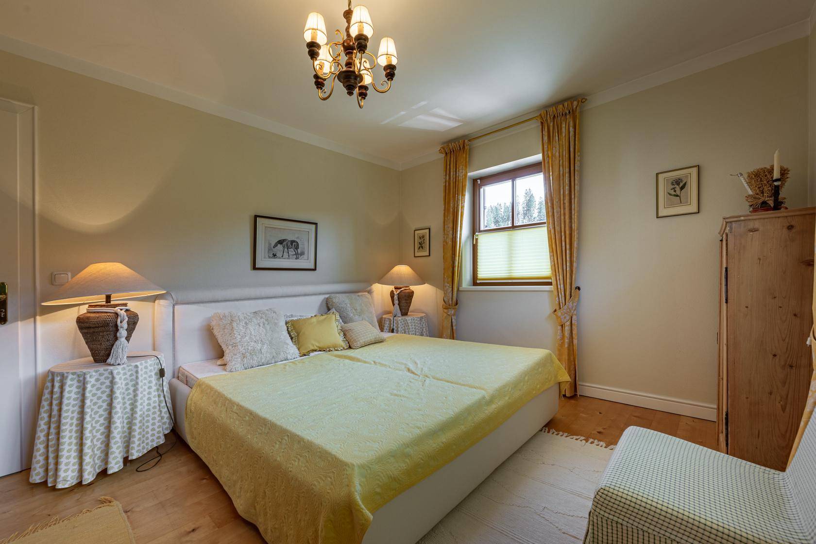 Gemütliches Schlafzimmer mit Doppelbett, Holzboden und traditioneller Einrichtung in hellen Farben.