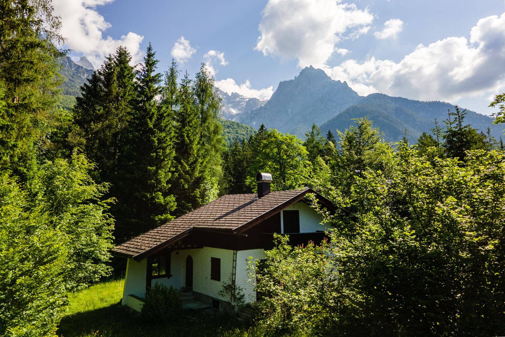 Charmantes Haus inmitten eines Waldes mit majestätischem Bergblick unter blauem Himmel.
