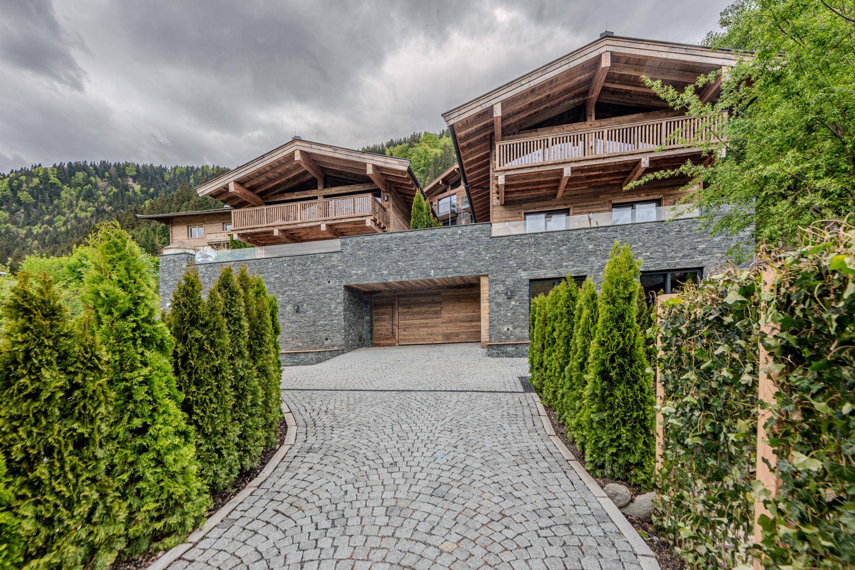 Zufahrt zu den luxuriösen Chalets mit Kopfsteinpflaster und gepflegten Hecken.