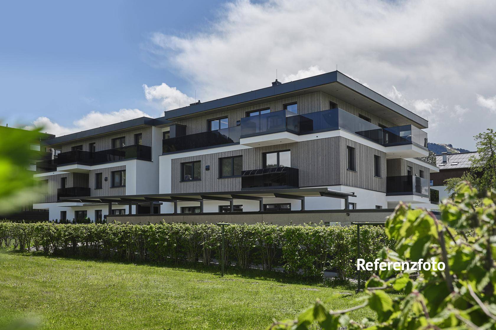 Modernes Wohngebäude mit Holzfassade, Balkonen und gepflegtem Gartenbereich im Vordergrund.