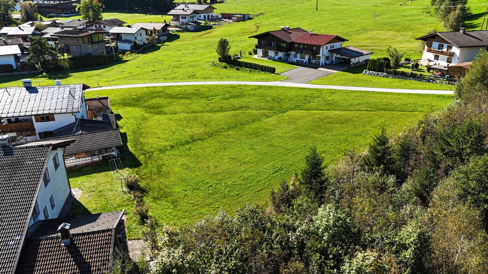 Blick von oben auf eine ländliche Wohngegend mit grünen Wiesen und traditionellen Häusern.