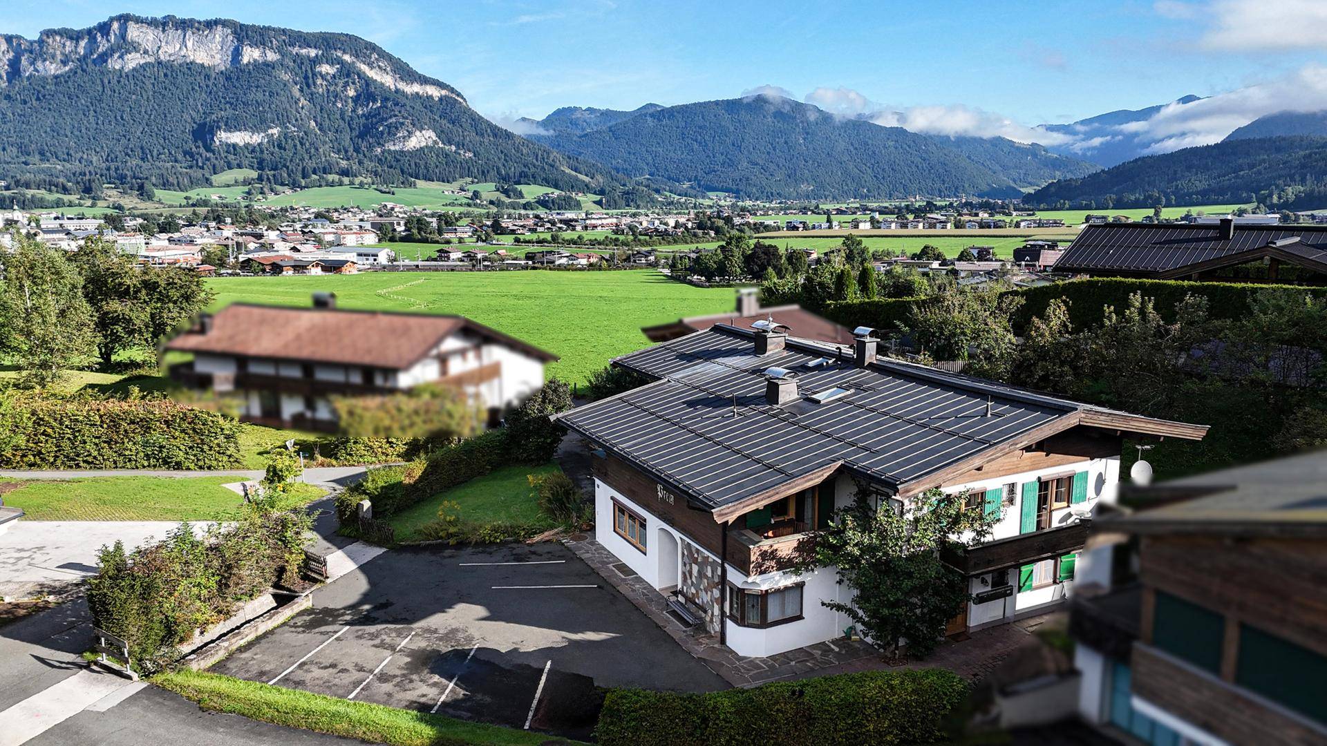 Luftaufnahme eines Hauses mit Solaranlage auf dem Dach, umgeben von grünen Wiesen und Bergen.
