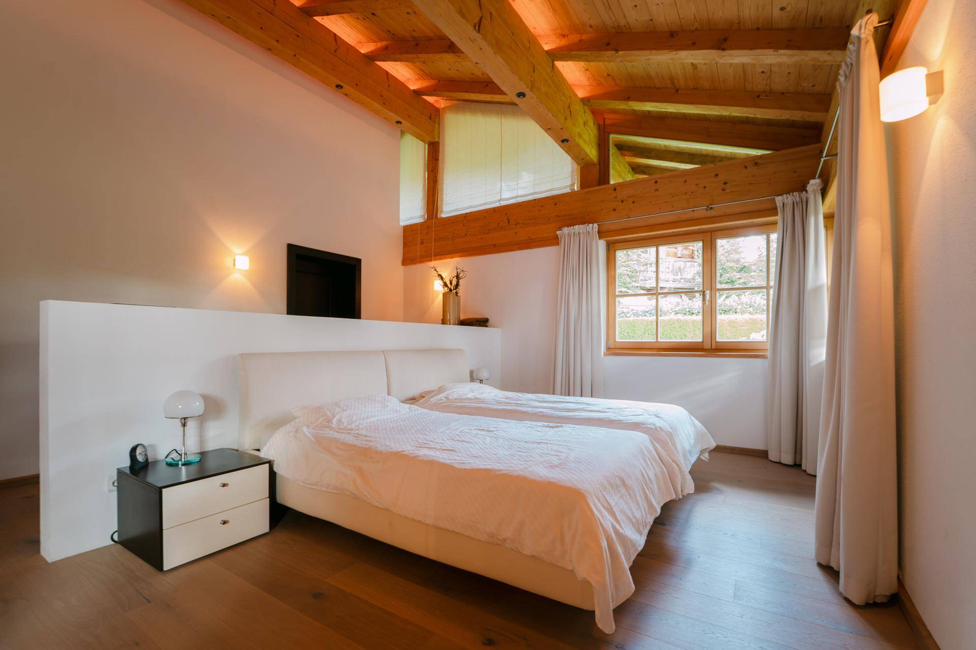Helles Schlafzimmer mit Holzbalkendecke und großem Doppelbett, bietet eine ruhige Rückzugsmöglichkeit.