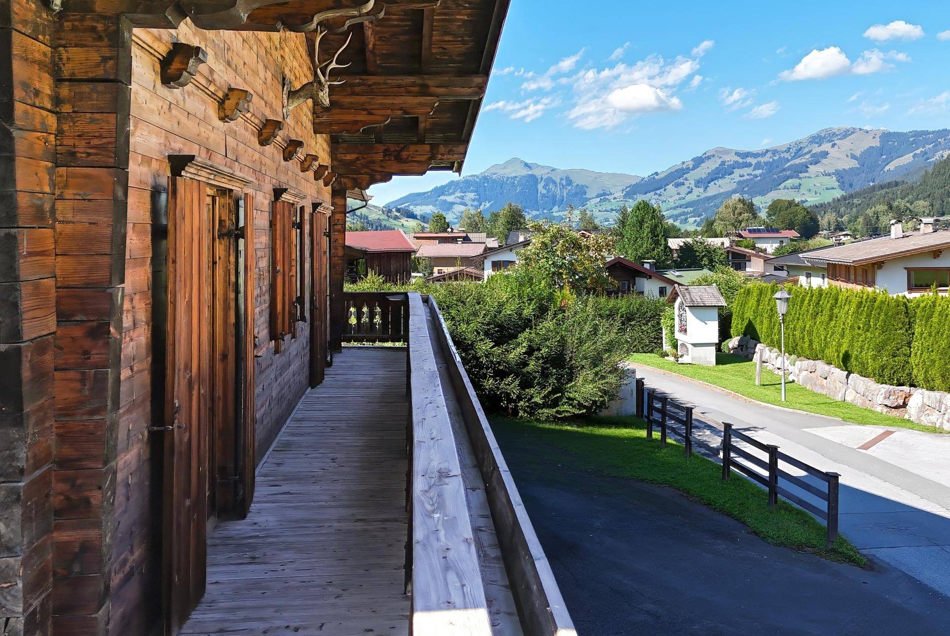 Langer Holzbalkon mit traditionellen Schnitzereien und weitem Blick auf die Berge und das Tal.