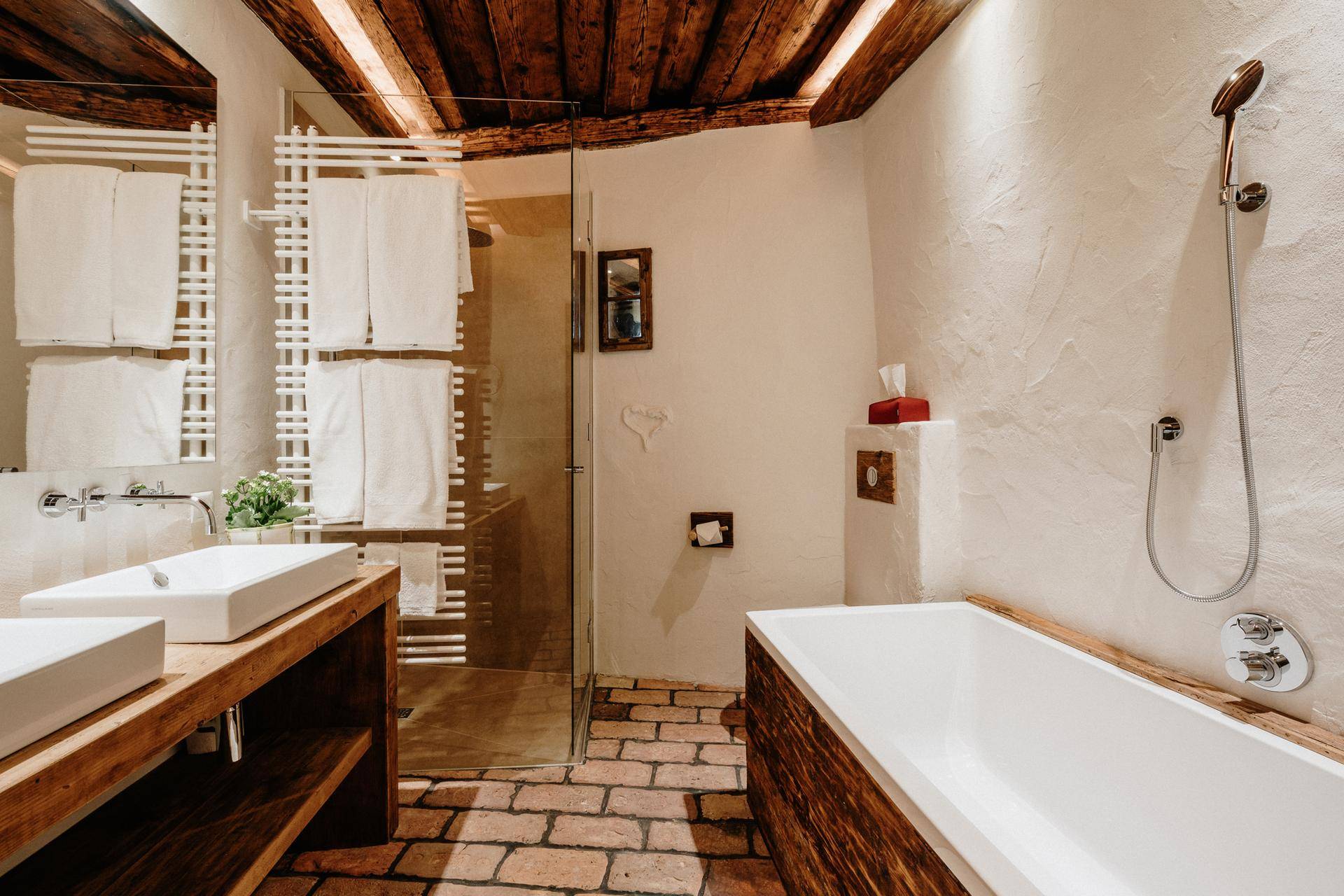 Rustikales Badezimmer mit Badewanne, begehbarer Dusche und Ziegelboden.