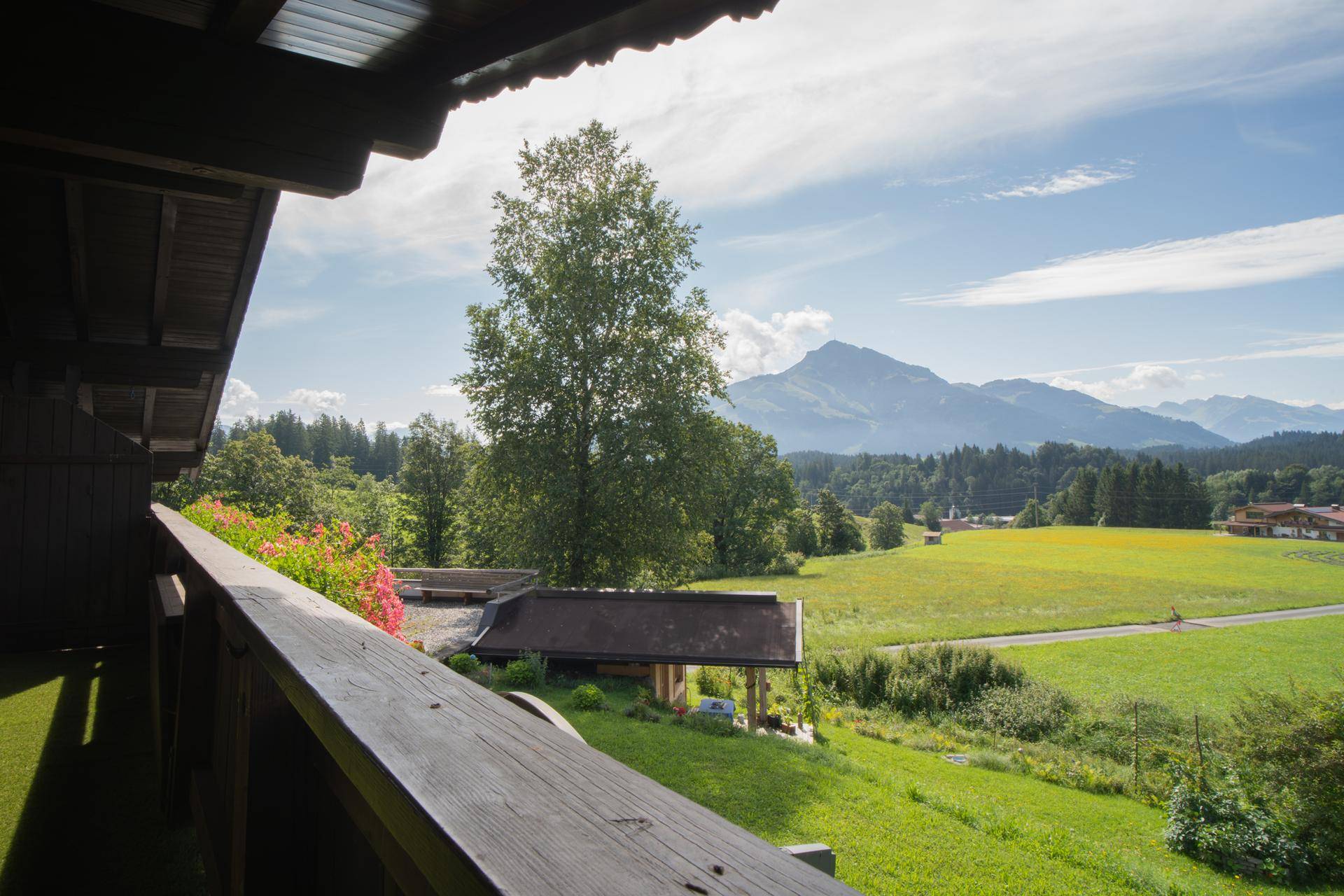 Balkon mit Holzboden und weitem Blick über grüne Wiesen und Berge.
