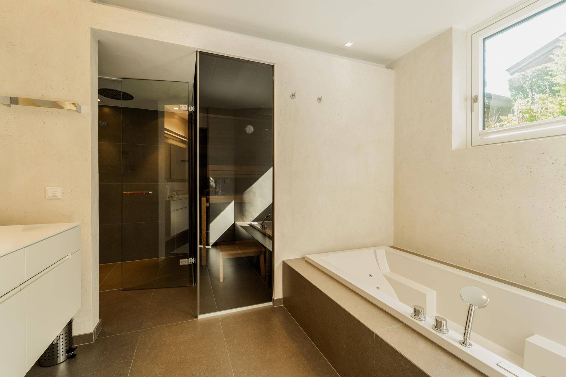 Luxuriöses Badezimmer mit Badewanne, begehbarer Dusche und integrierter Sauna.